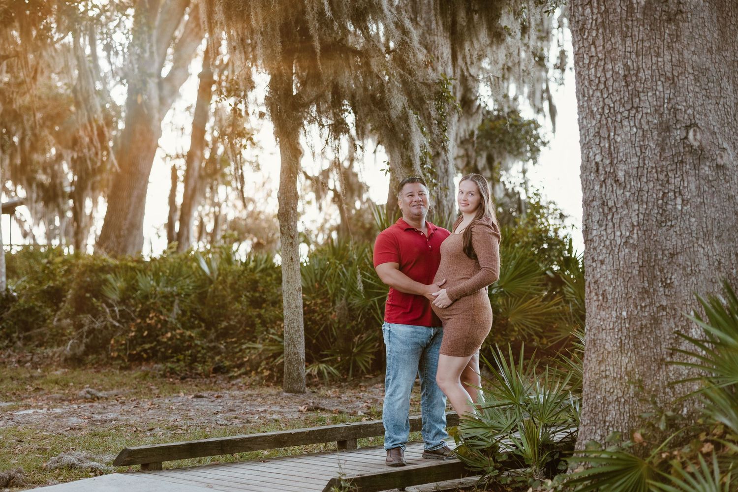 Maternity photo shoot in wooded area with trees and natural lighting.