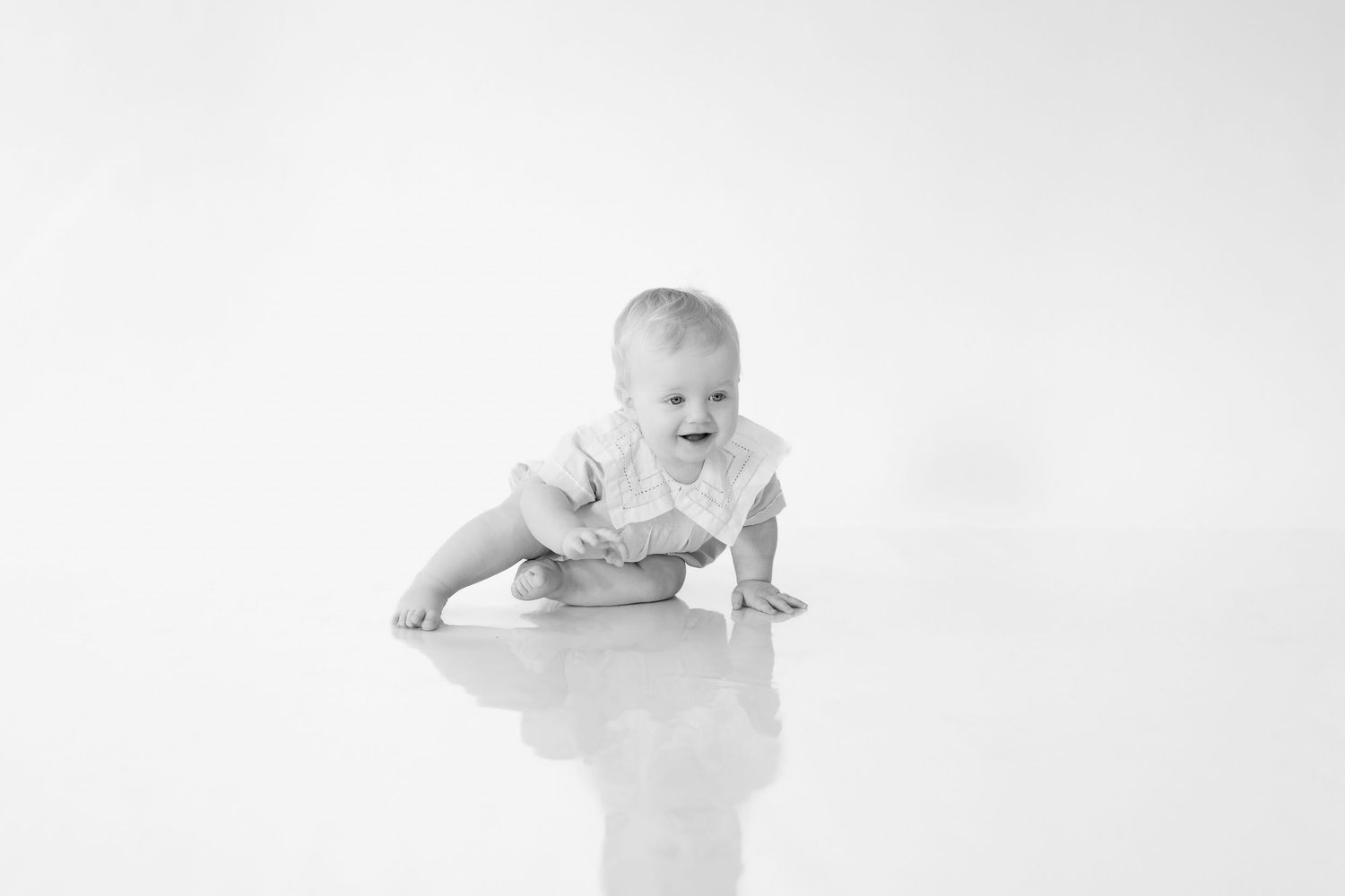 A sequence of four black and white photos showing a baby crawling and moving across a light background.