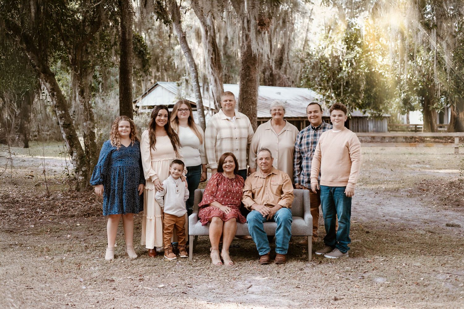 Large family group portrait outdoors with Spanish moss trees in background.