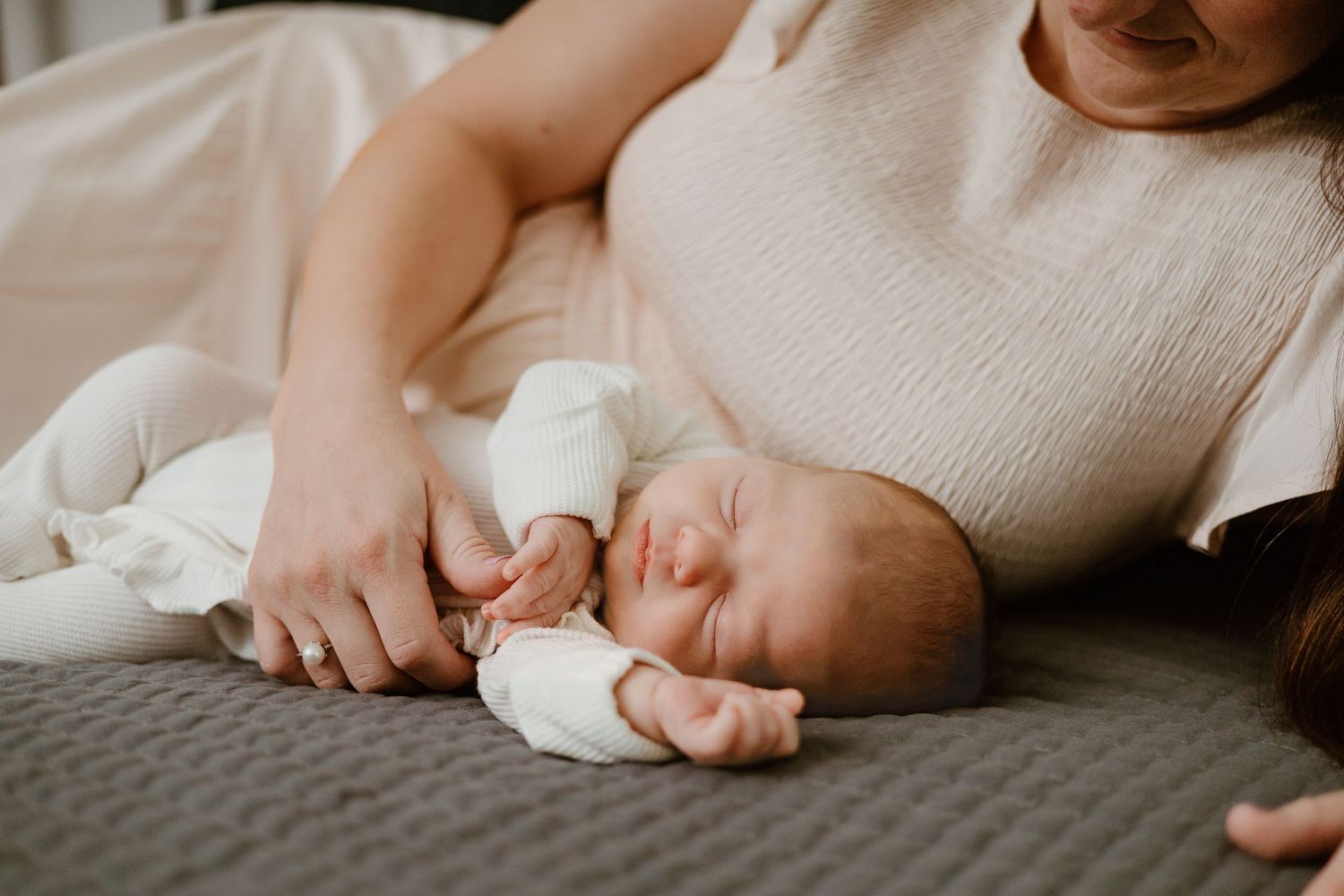 Close-up of a sleeping baby's hand being gently touched.