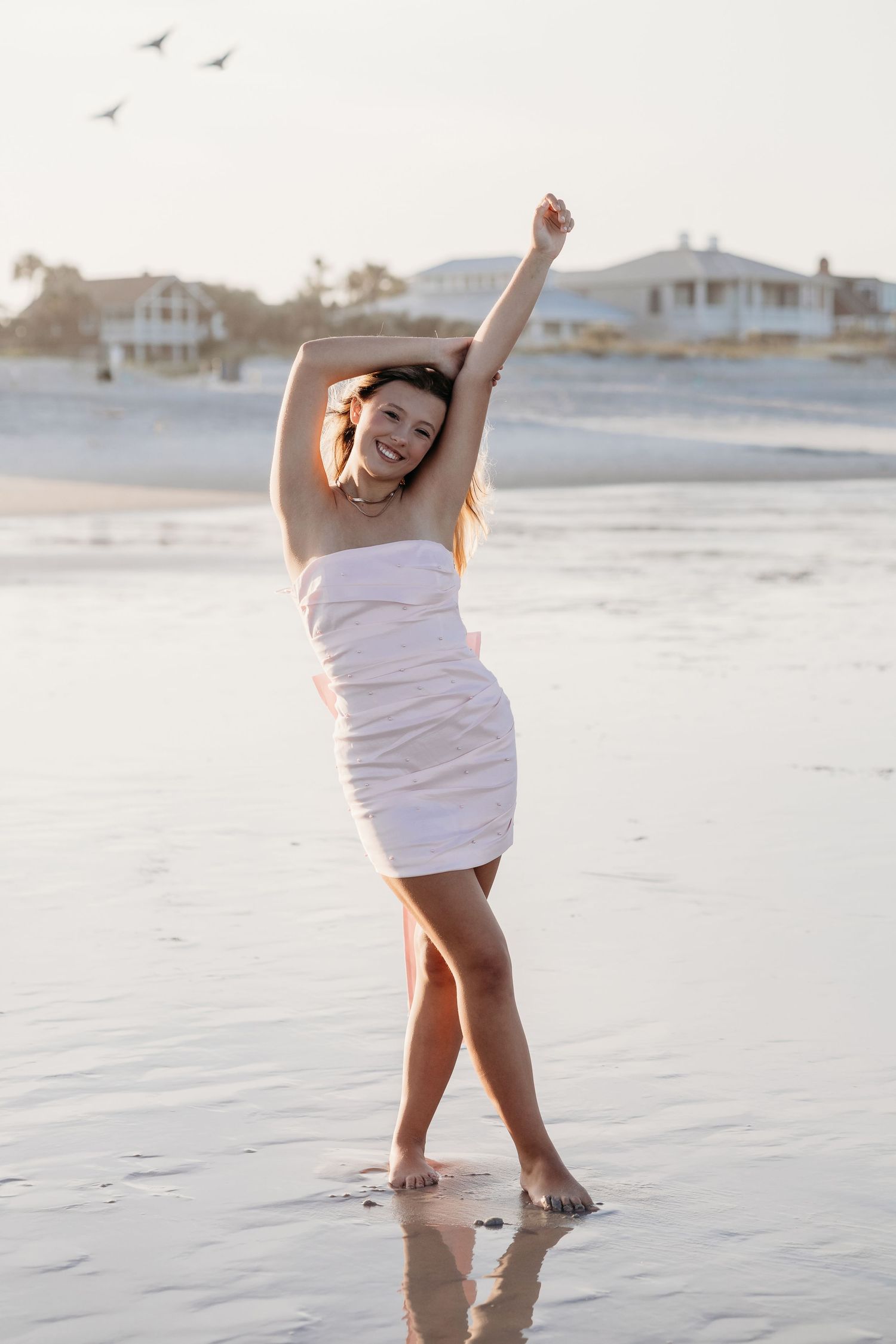 Dancing sequences on a white sandy beach at sunset with waves in the background.