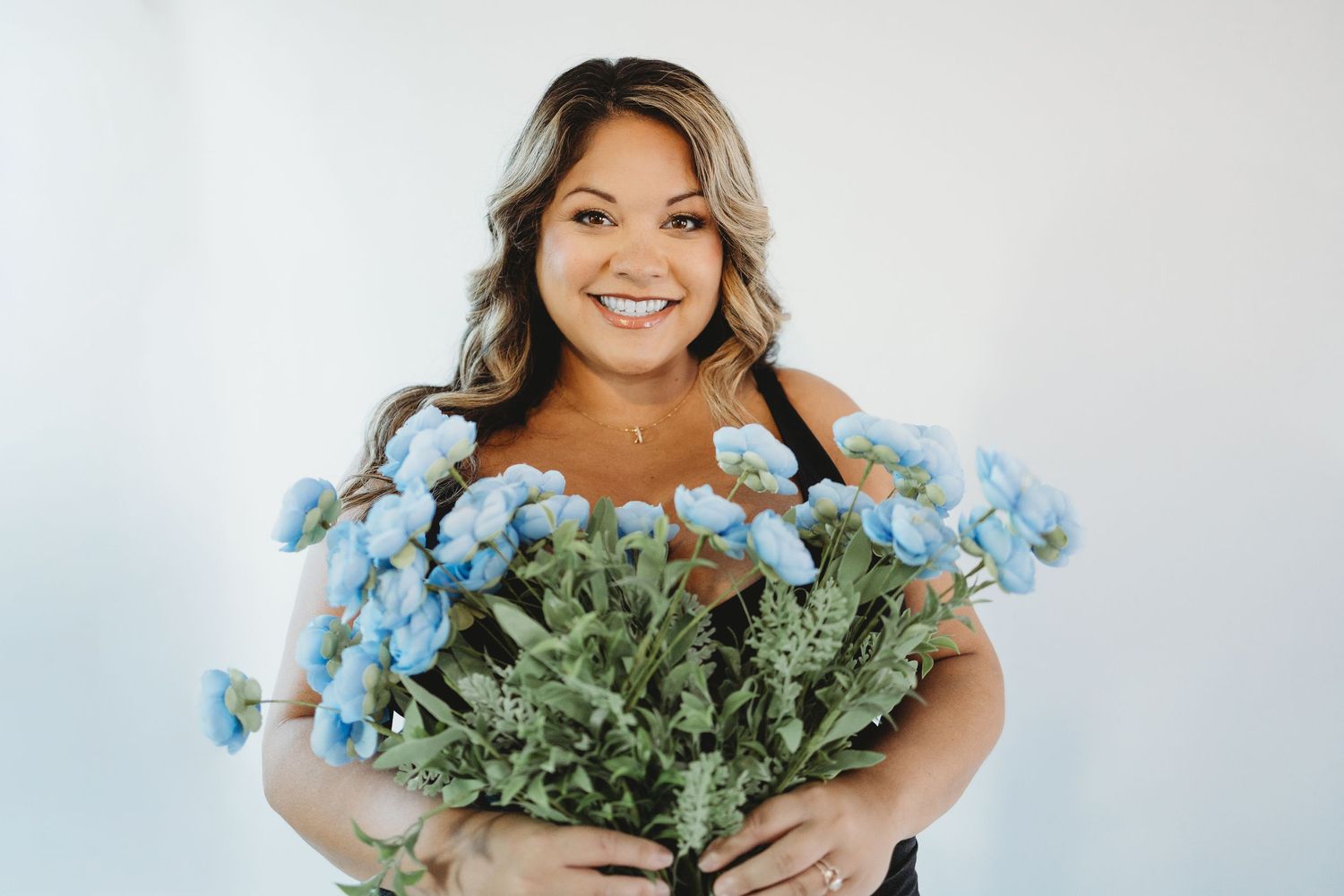 A person holds a large bouquet of light blue flowers with dusty miller foliage against a white background.