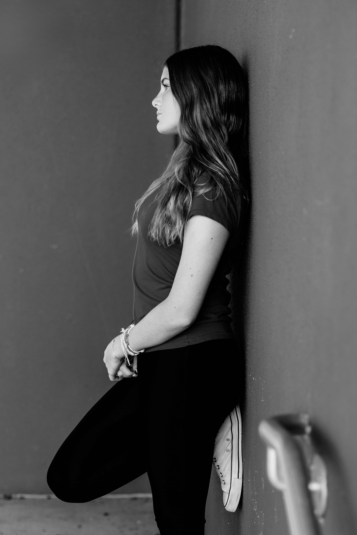Artistic black and white portrait series against a dark wall.