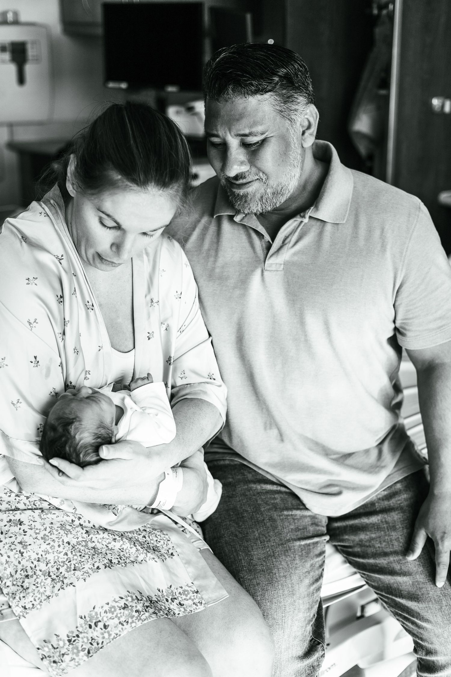 Black and white photo of parents bonding with their newborn baby.
