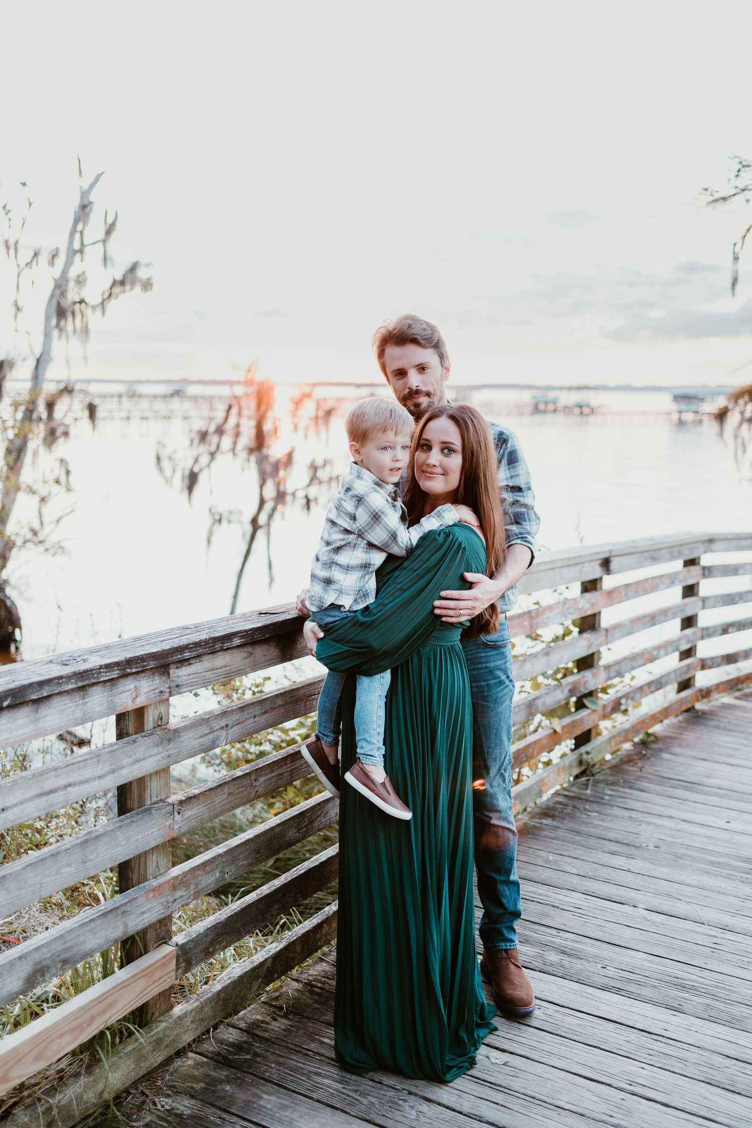 A group stands together on a wooden boardwalk at sunset with Spanish moss and water in the background.