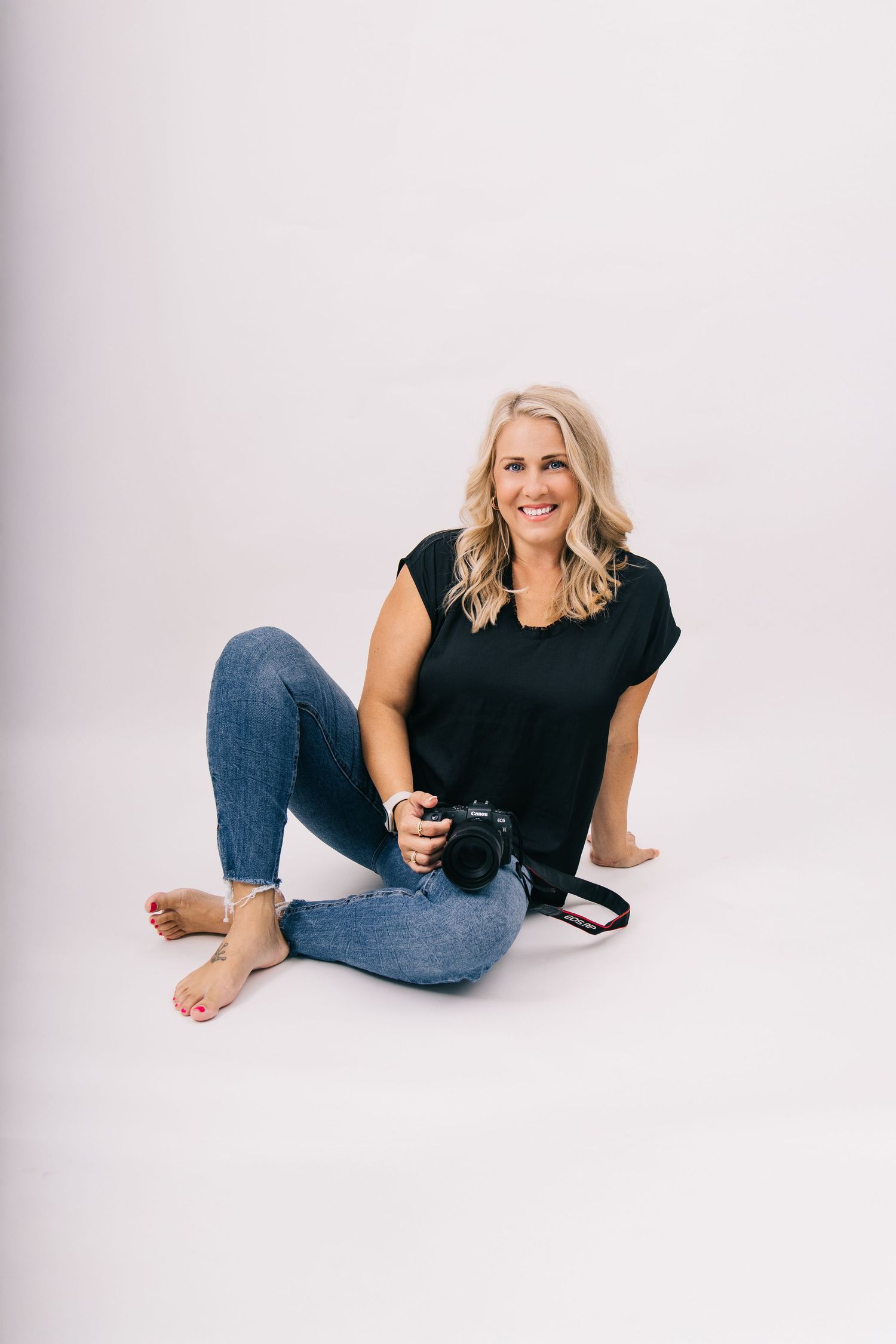 Professional lifestyle photoshoot showing casual poses against white backdrop wearing black top and jeans.