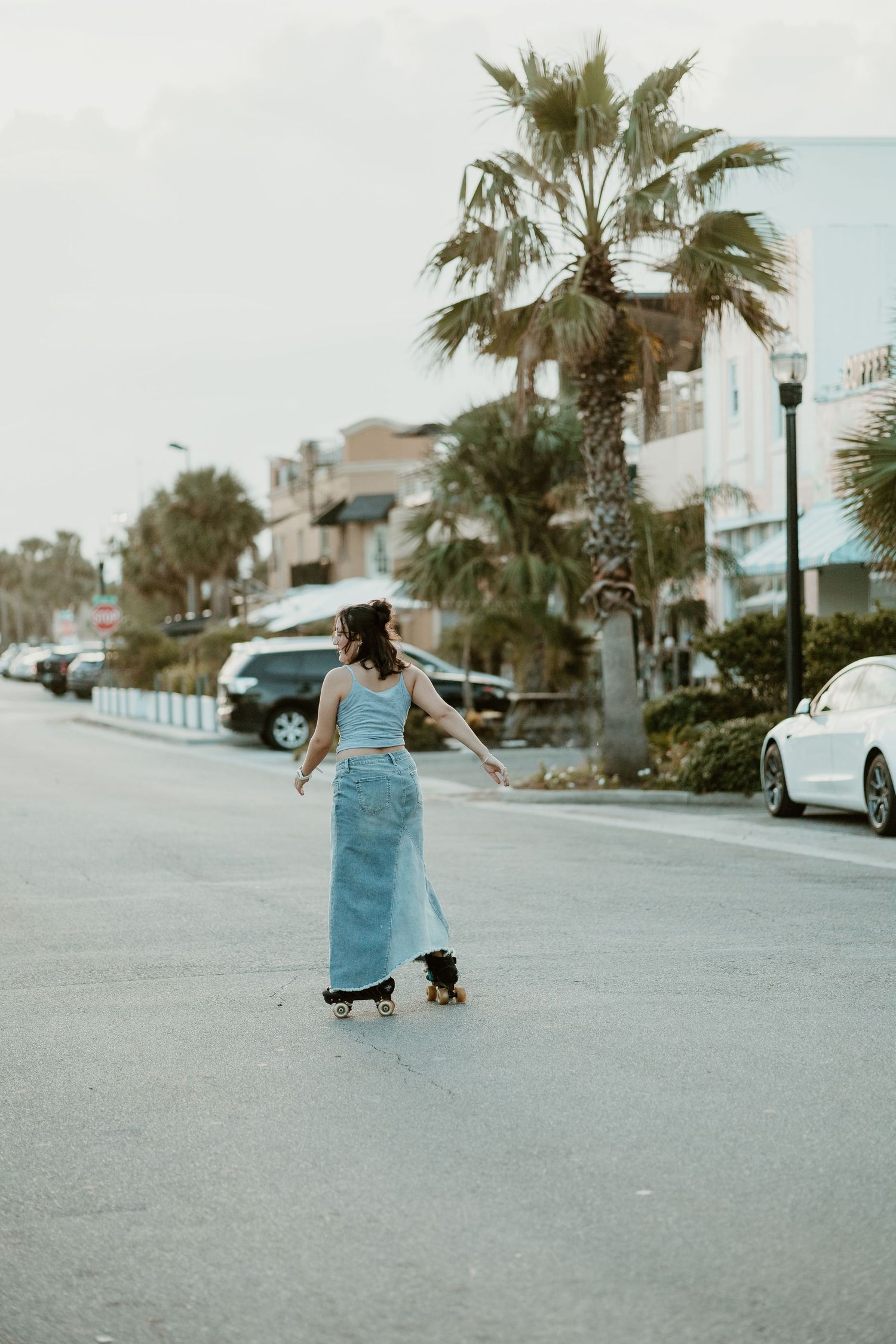 Carefree dance movements on a coastal street with palm trees and parked cars.