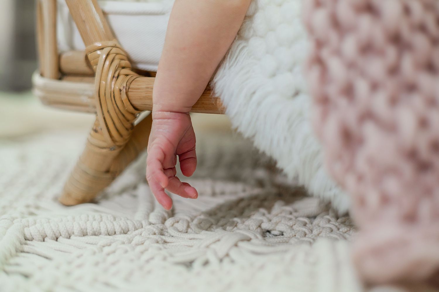 Close-up of tiny baby hands grasping soft white textured fabric.