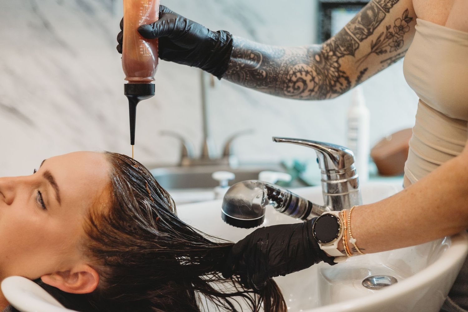 Professional hair washing service being performed at modern salon basin.