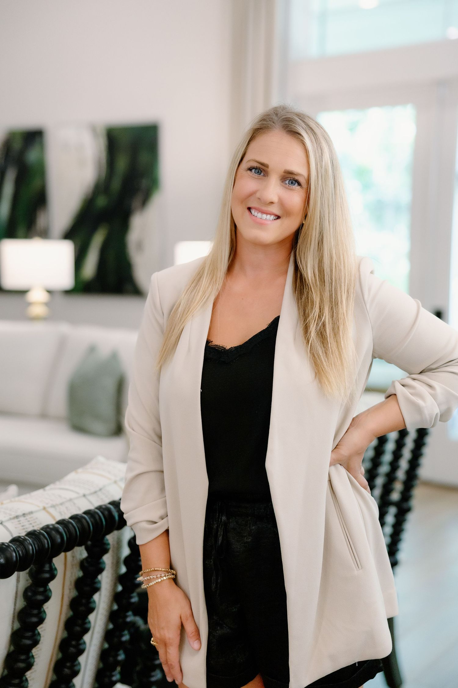 Professional headshots in bright office setting wearing cream blazer and black top.