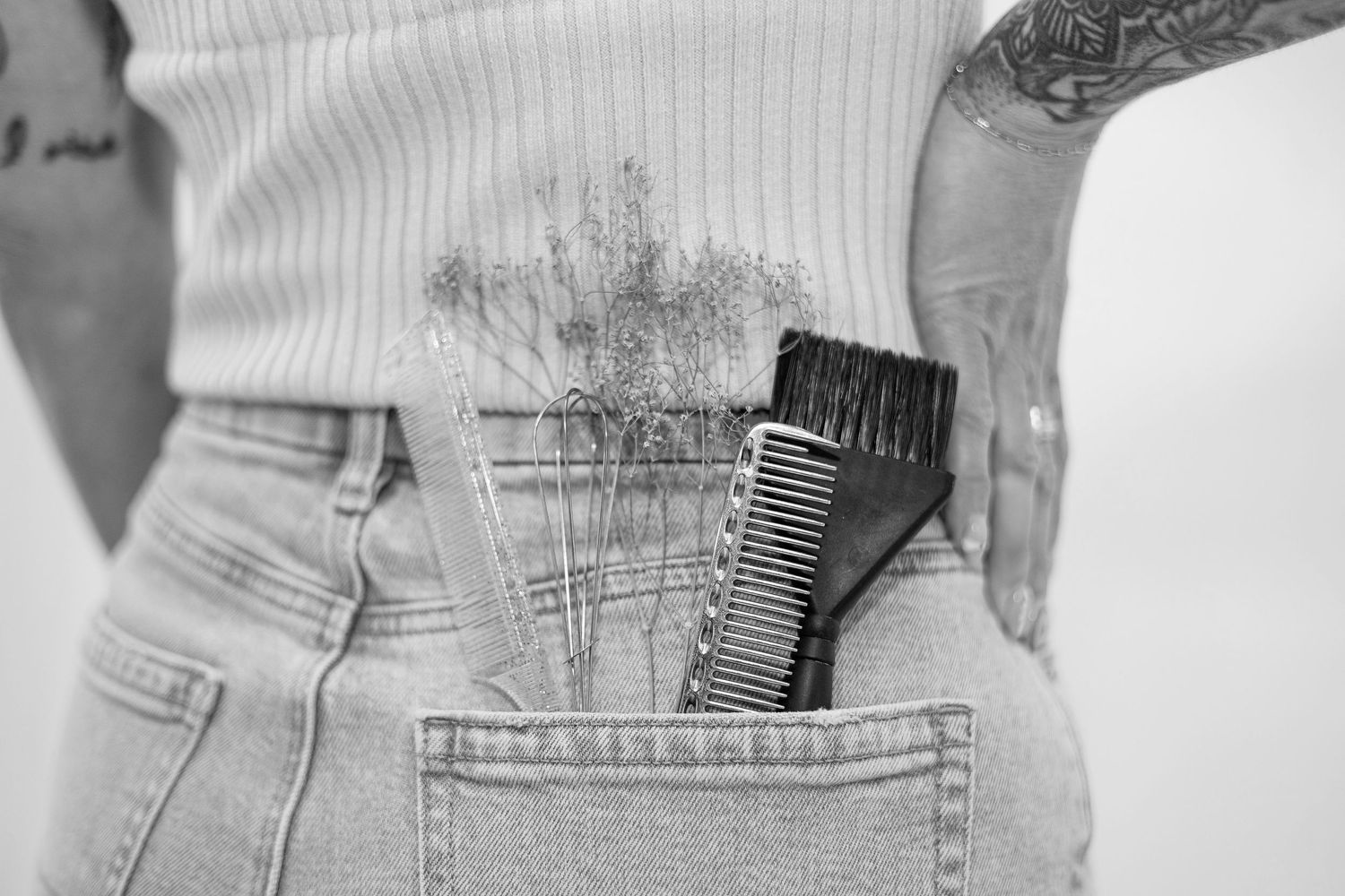 Close-up detail of denim jeans and tattoos against white background.