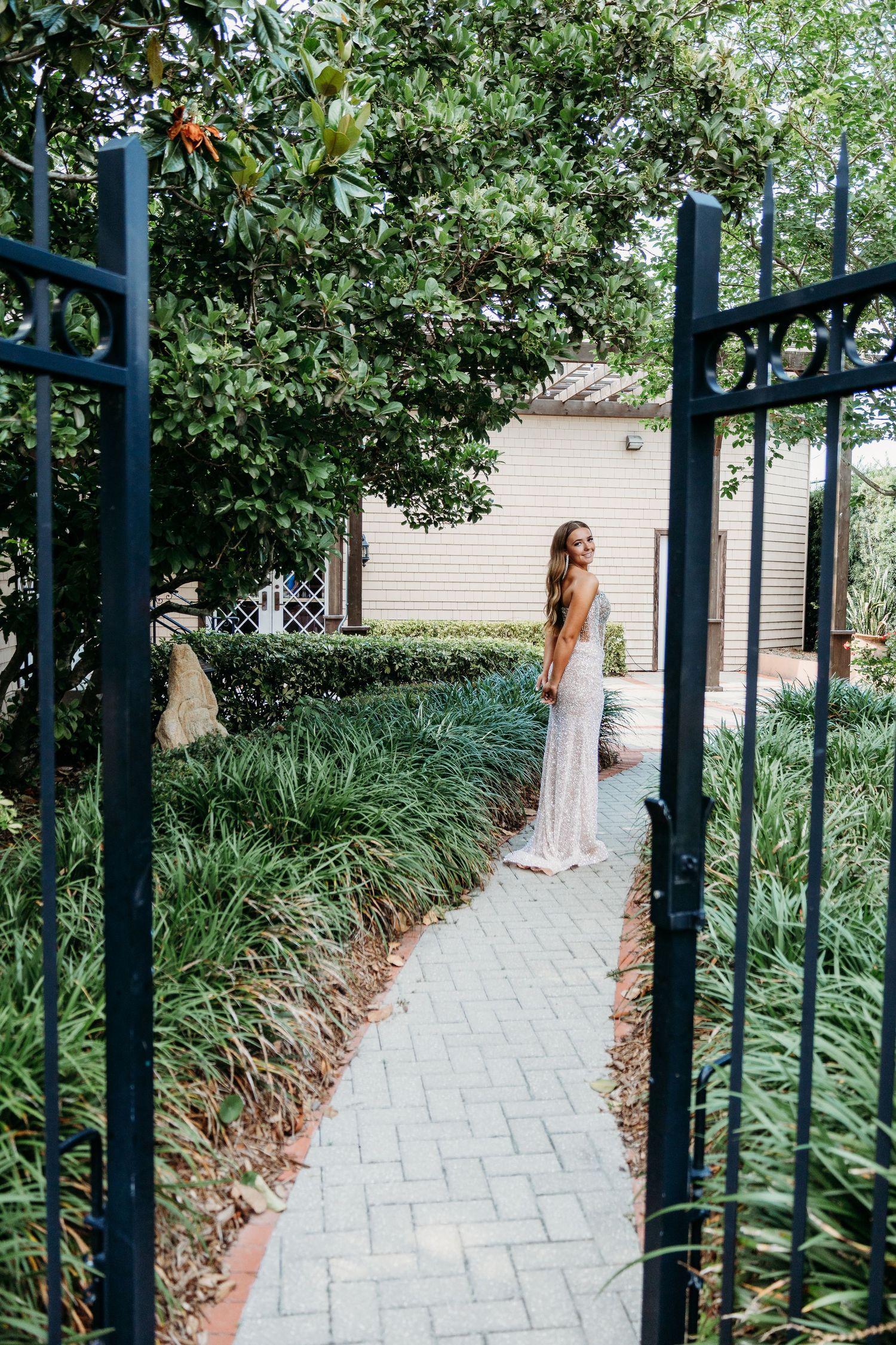 A garden pathway lined with blue metal posts and lush greenery leads through a serene outdoor setting.