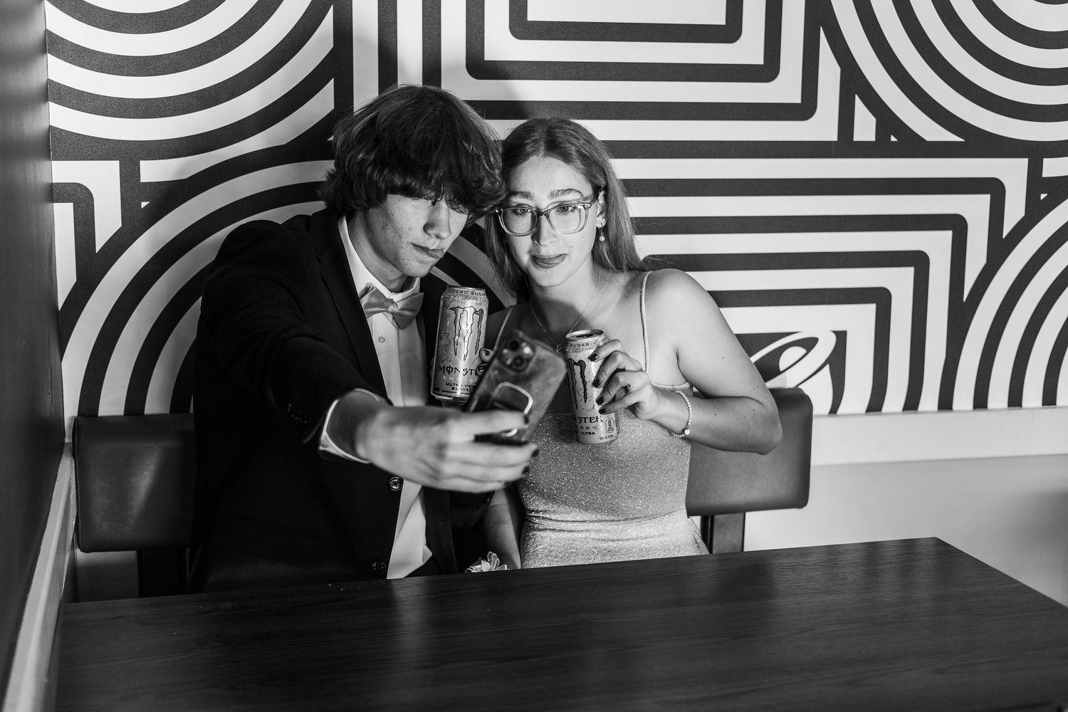 Couple sharing an intimate moment in front of a geometric black and white wall pattern.