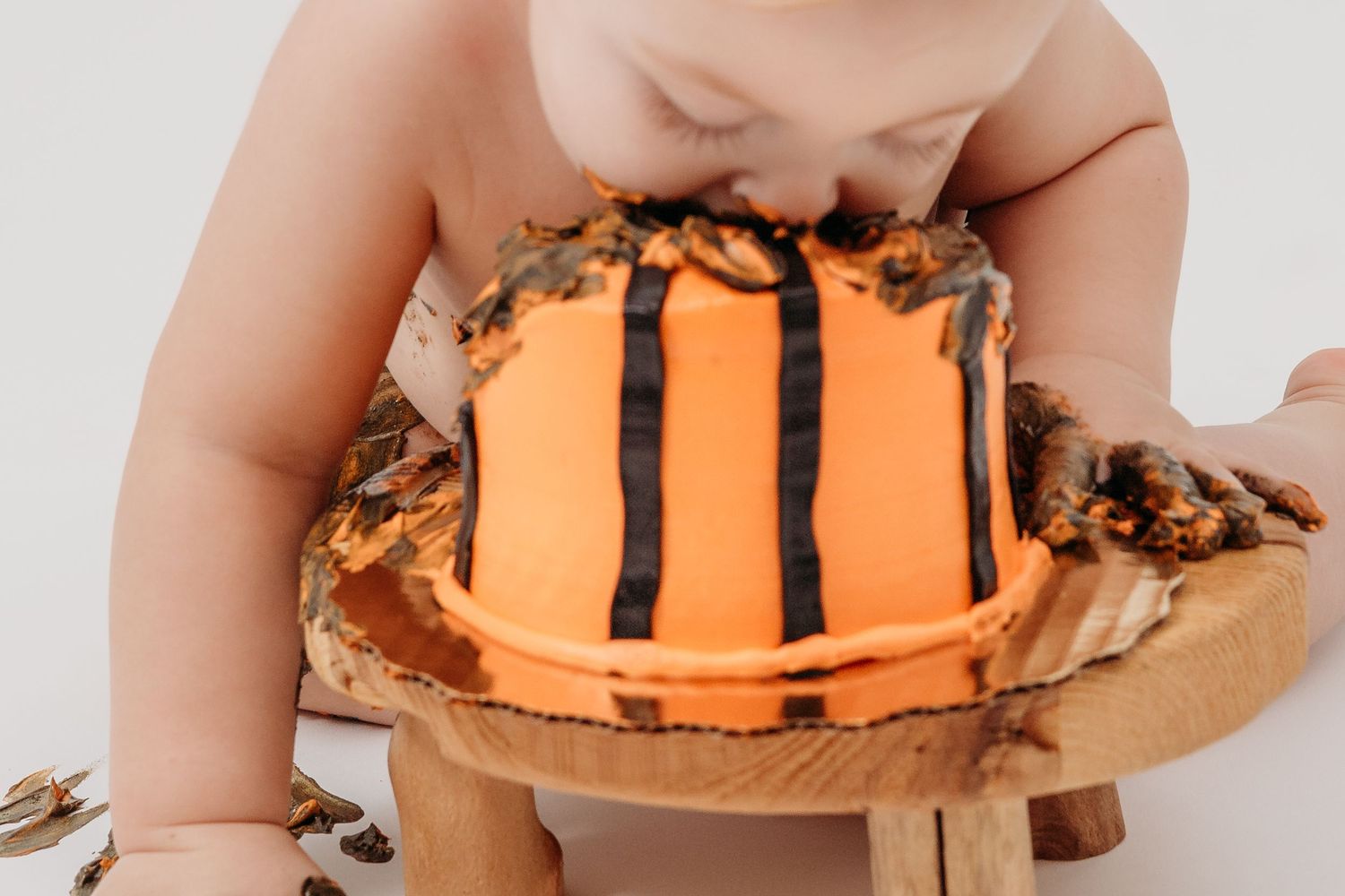 Baby smashing into orange basketball cake on wooden board.