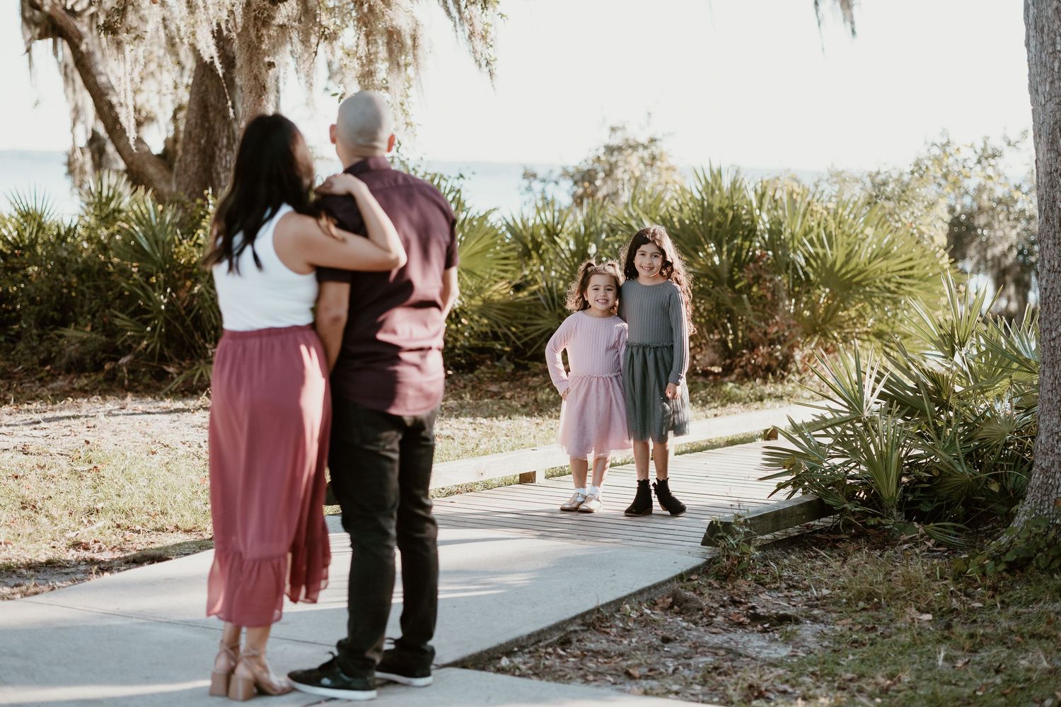 A candid family moment captured on a tree-lined pathway during golden hour.