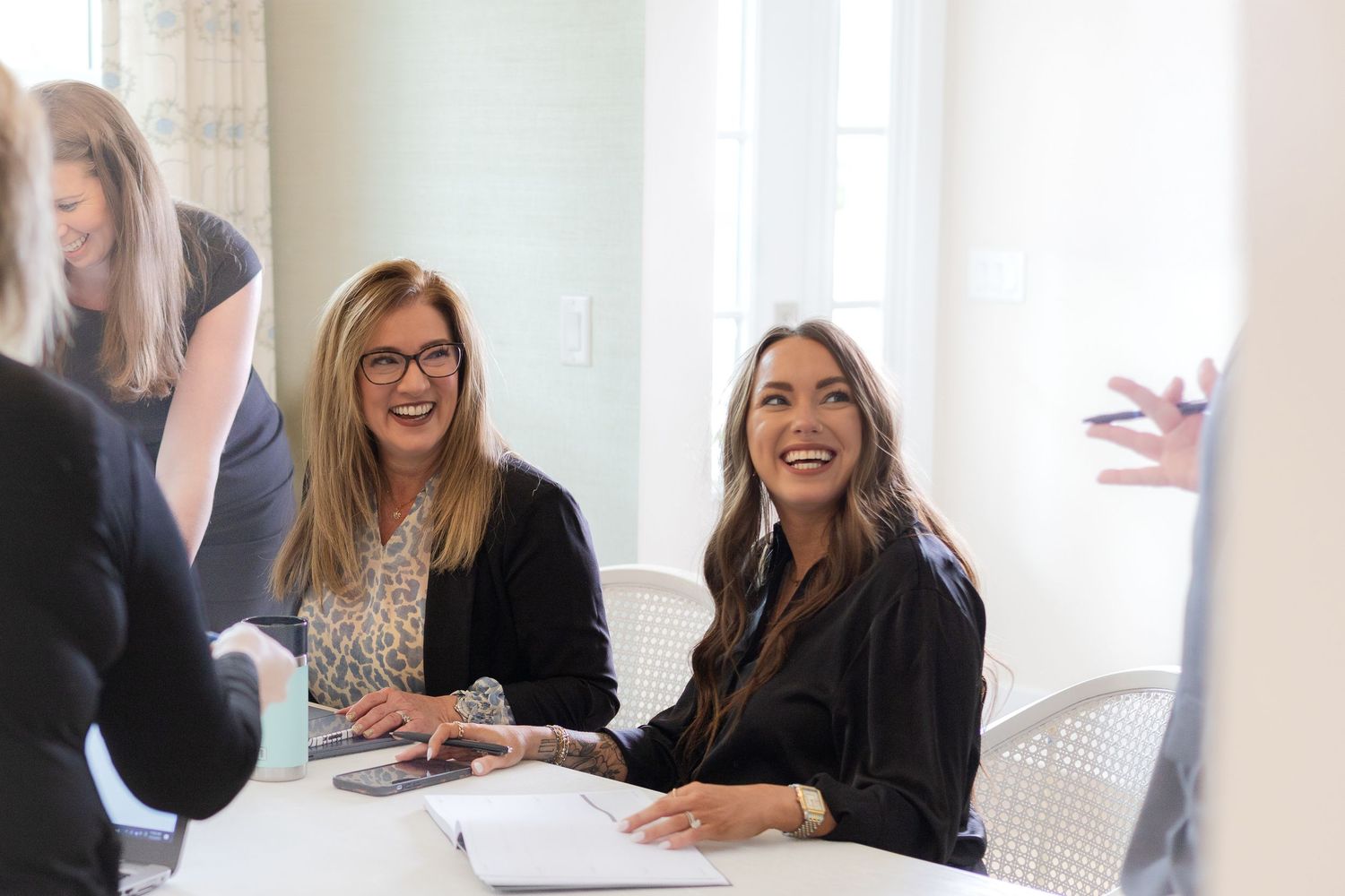 Professional women smiling during a business meeting at a bright modern office.