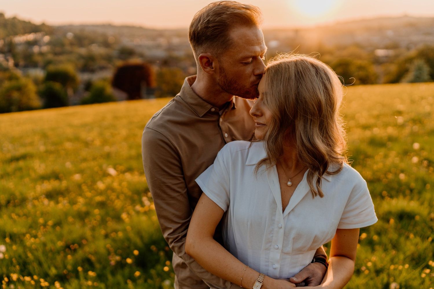 A couple shares tender moments in a golden meadow during sunset, creating a romantic outdoor photoshoot sequence.