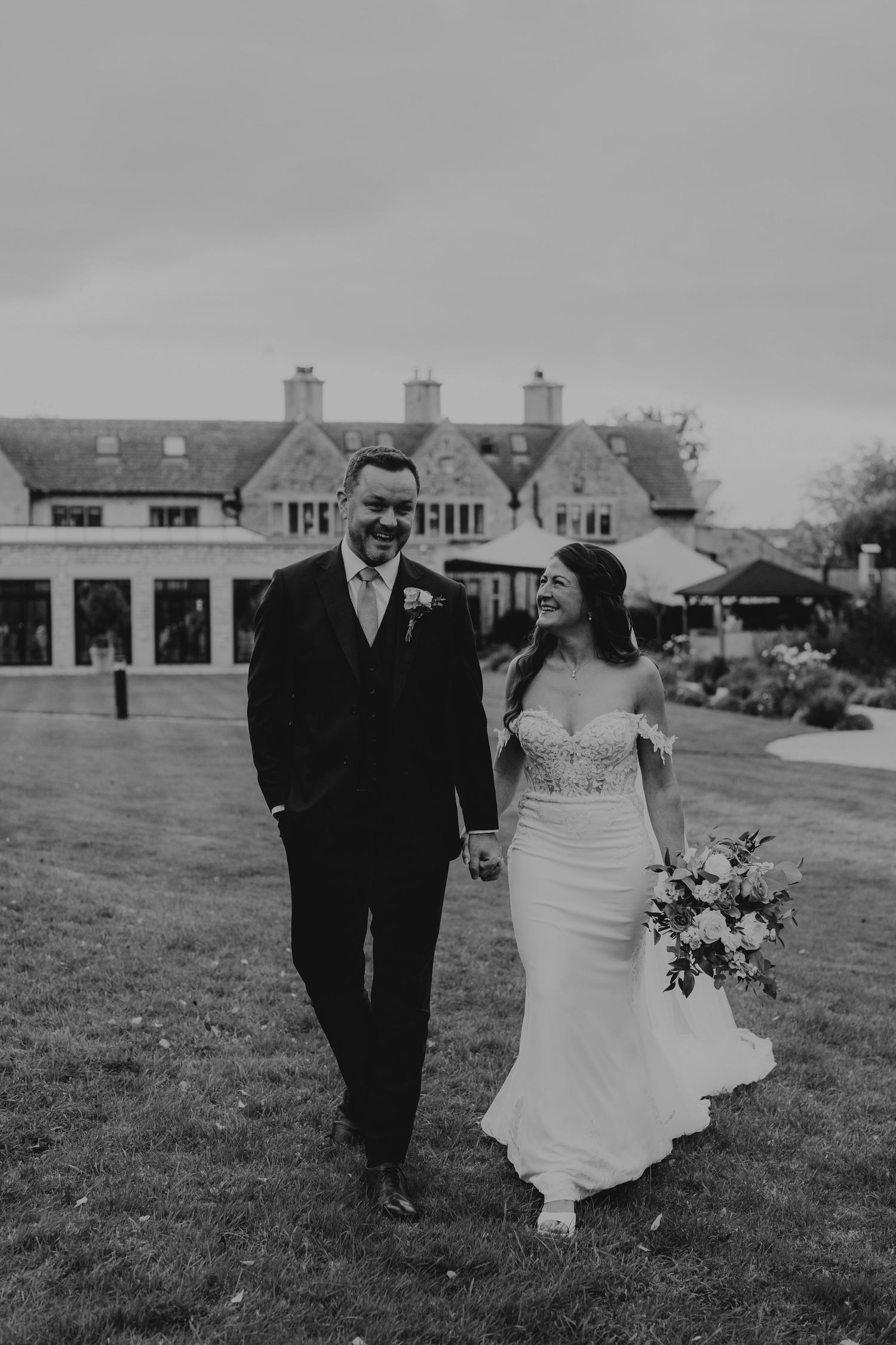 Smiling bride and groom walking hand in hand on the lawn at the wedding venue pear tree in purton