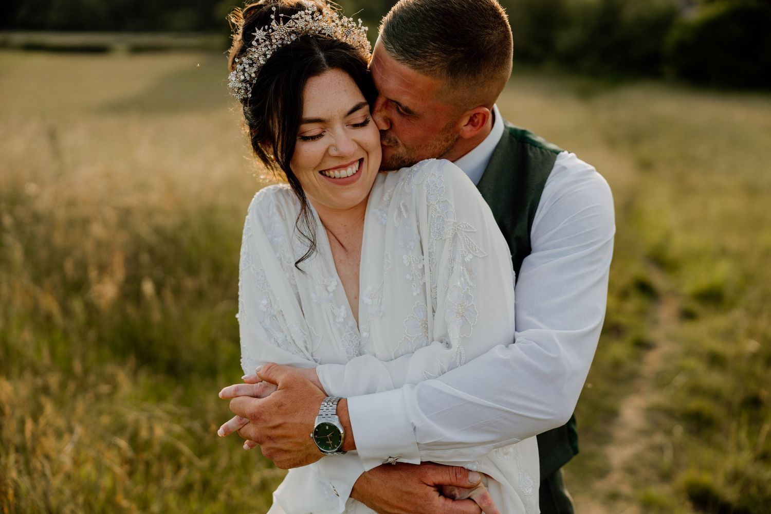 wedding couple embraces tenderly in a golden sunlit meadow during a romantic outdoor photoshoot.