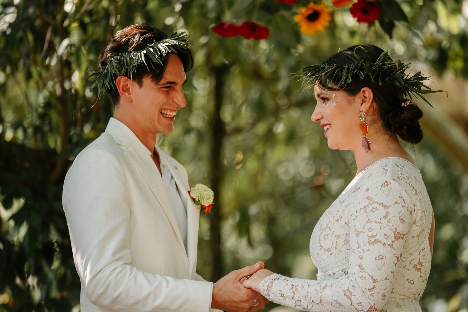 A wedding celebration outdoors with people in white attire surrounded by lush greenery and natural lighting.