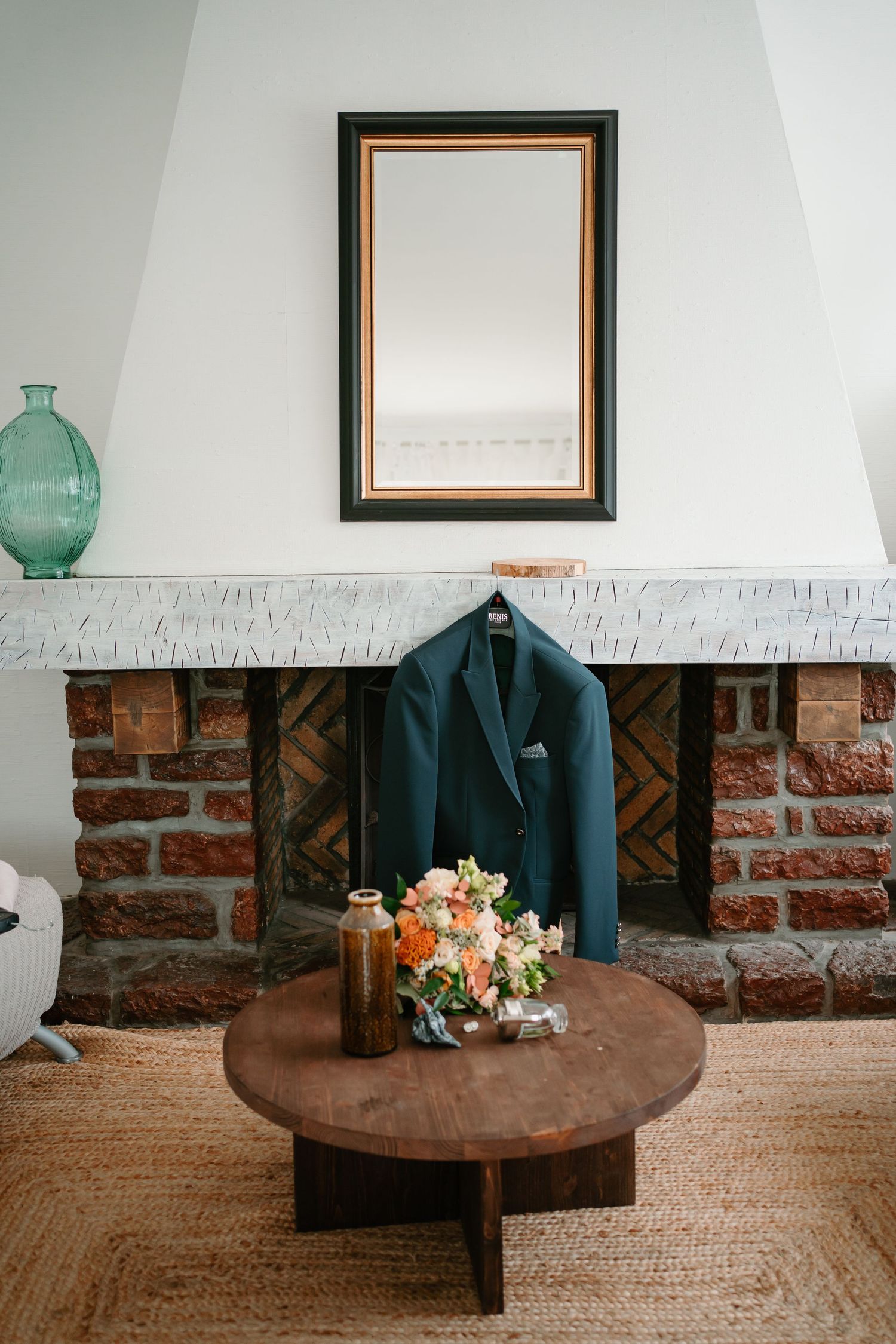 A series of four minimalist vignettes with a rustic wooden table, black coat, and floral arrangement against brick walls.