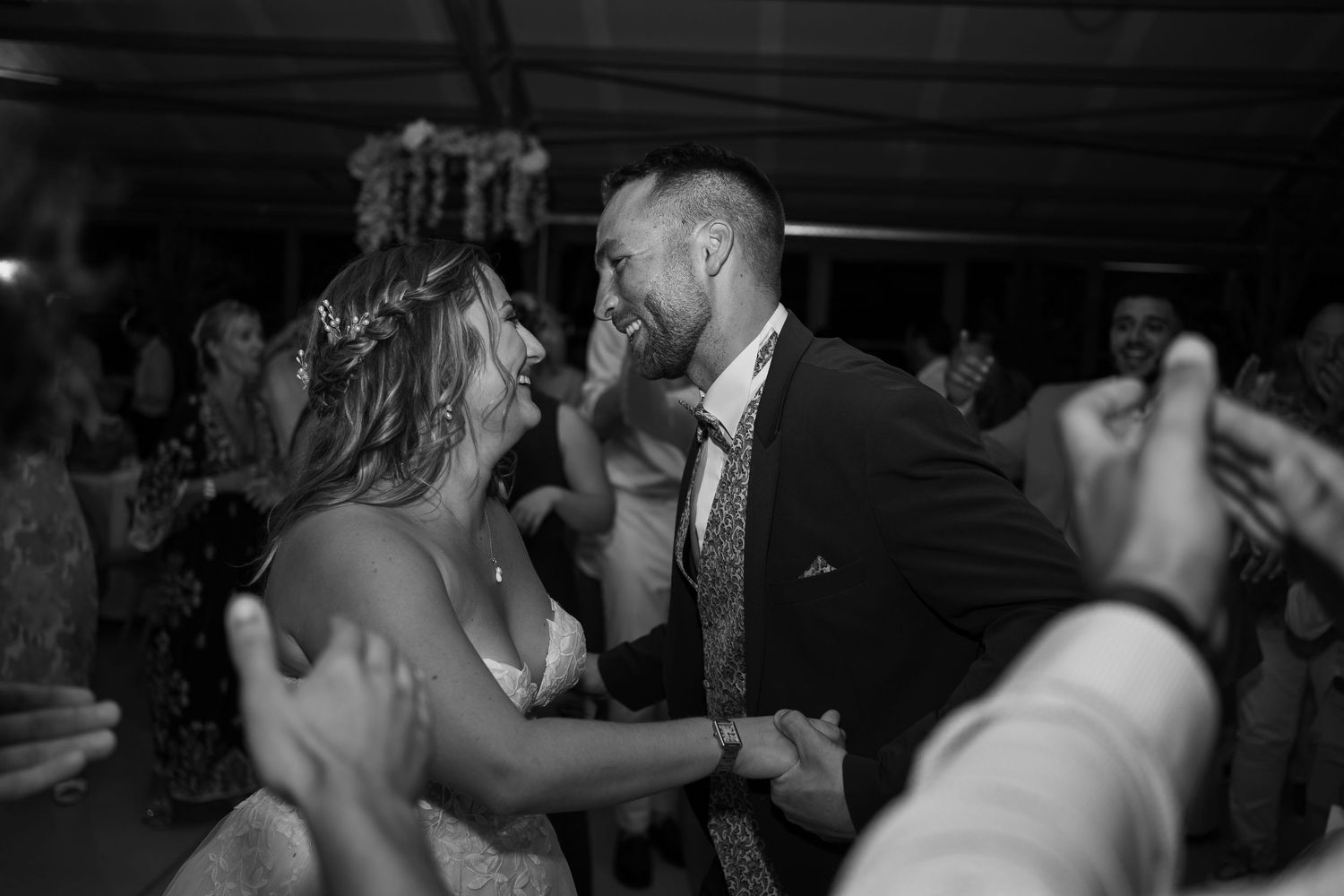 A couple dances joyfully together at a wedding reception in black and white photography.