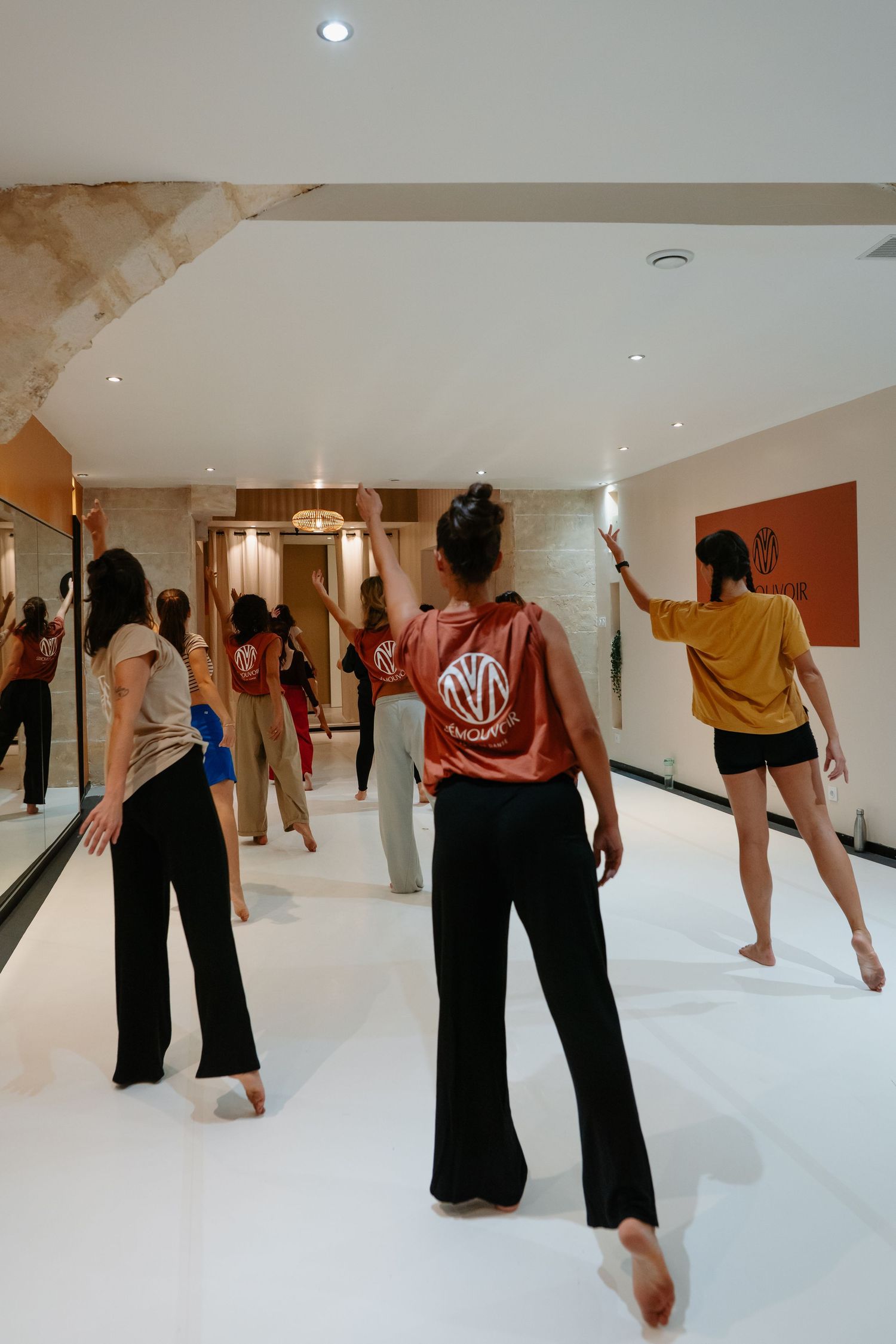 Dance students practicing modern dance movements together in a bright white studio space.