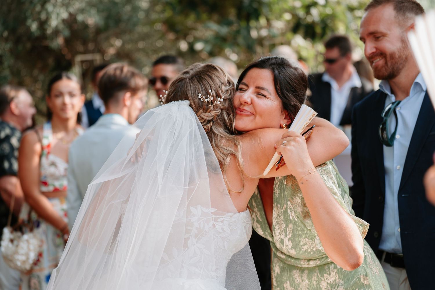 Wedding guests celebrate and dance together at an outdoor reception party under natural lighting.