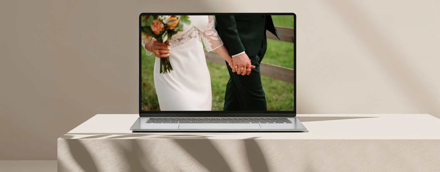 A couple holds hands during an outdoor wedding ceremony with guests seated on white chairs in a garden setting.