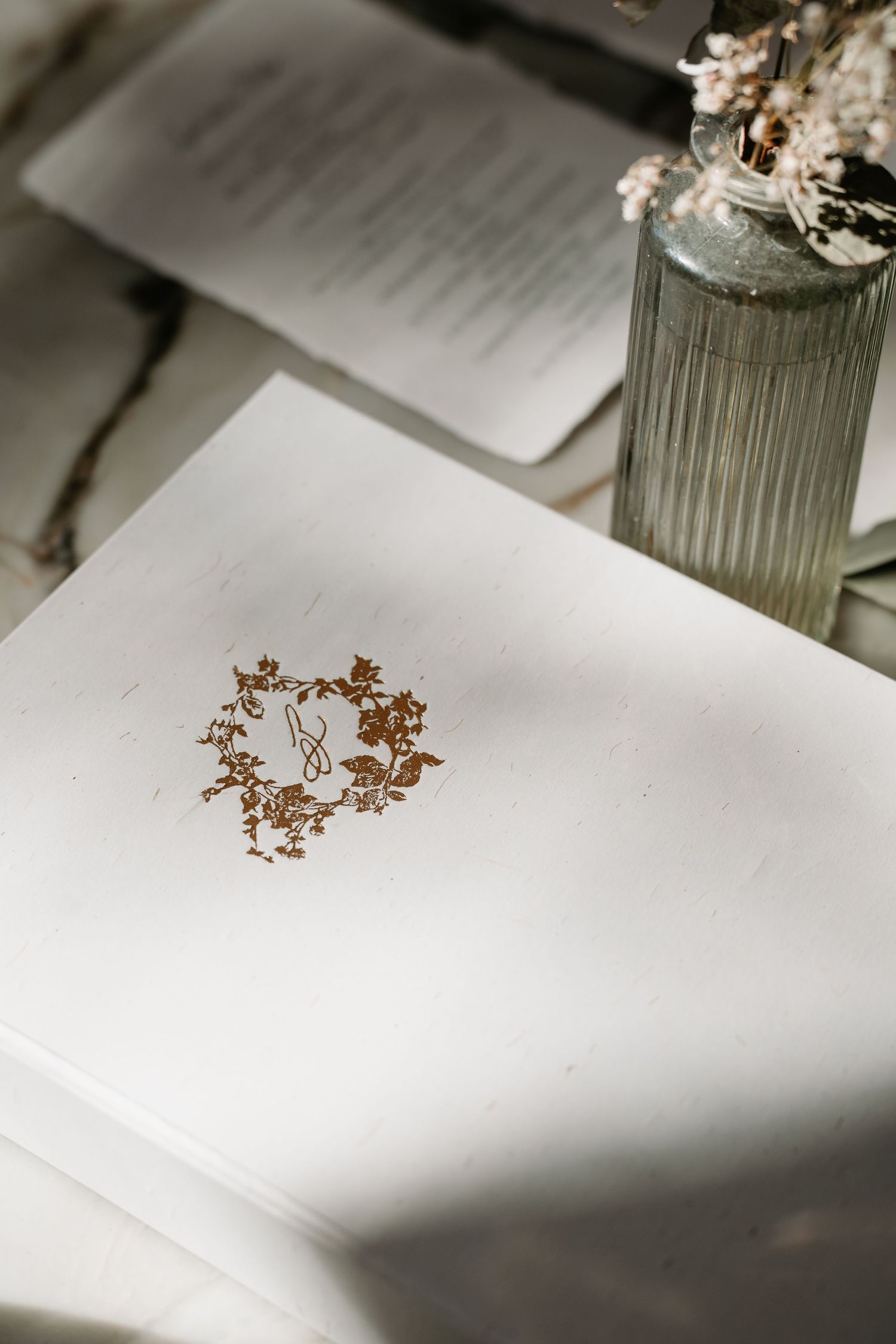A series of minimalist photographs showing dried flowers casting shadows on white paper in varying compositions.