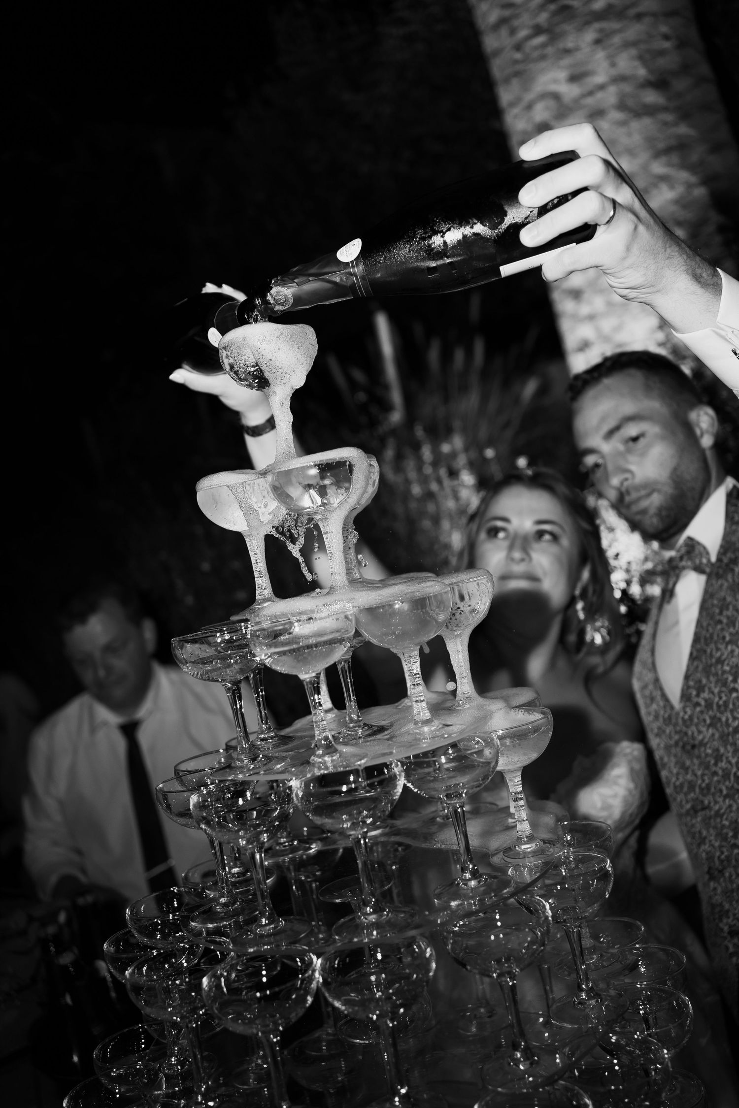 Black and white photos show a champagne tower being built at an elegant party celebration.