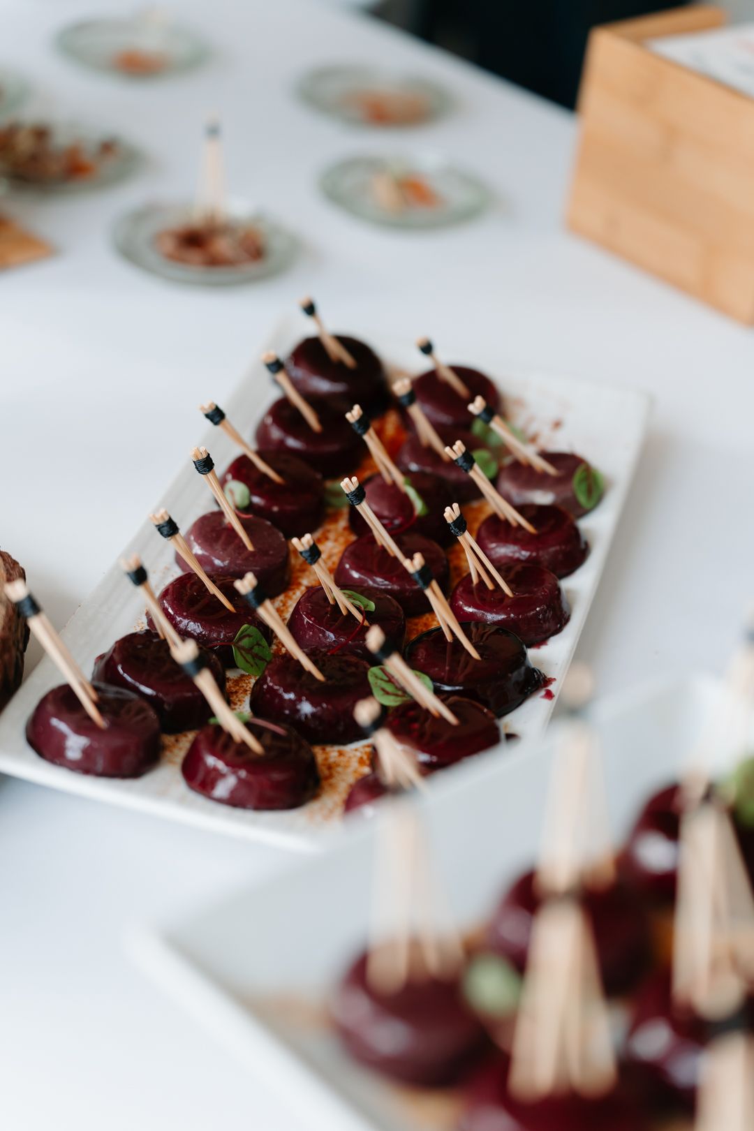 Elegantly plated appetizers featuring dark purple elements arranged on white serving platters.