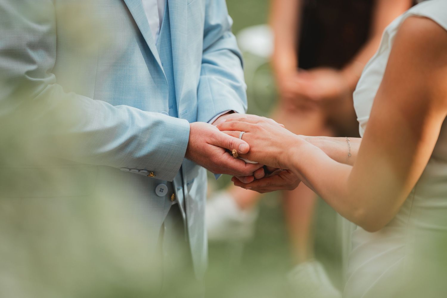 Close-up of wedding ceremony hands and ring exchange in soft natural light.
