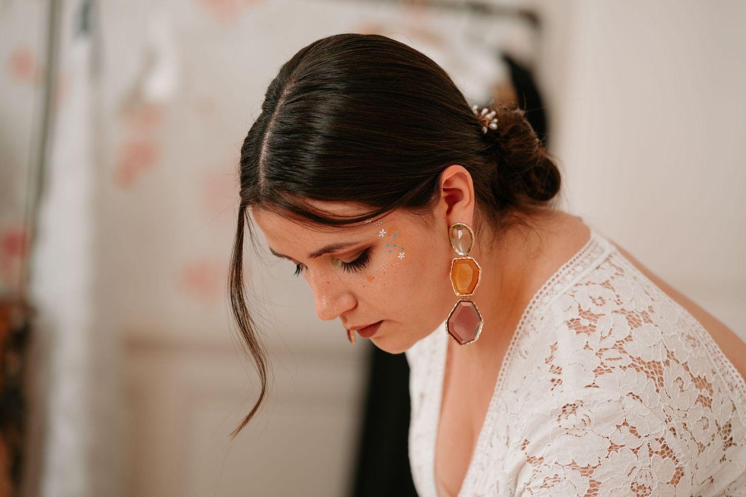 Side profile of a bride wearing a delicate white lace dress and gold hoop earrings with her hair in an elegant updo.