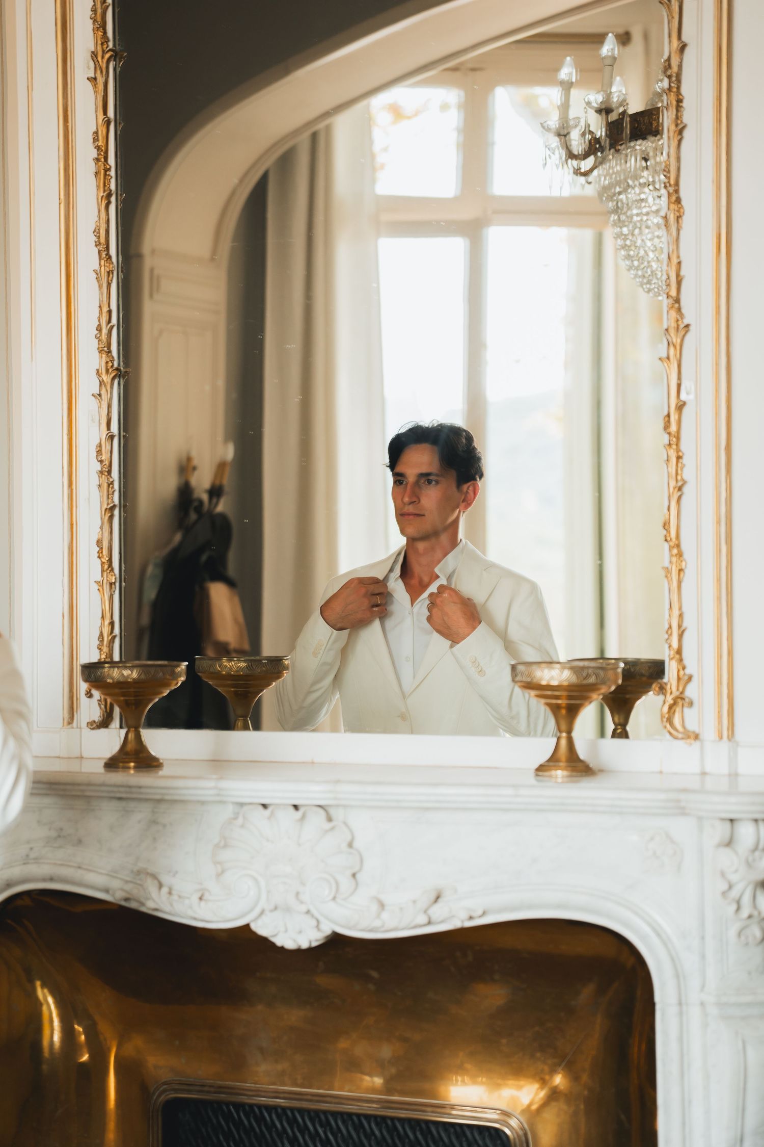 Person in white shirt standing in elegant room with ornate mirrors and golden accents on walls.