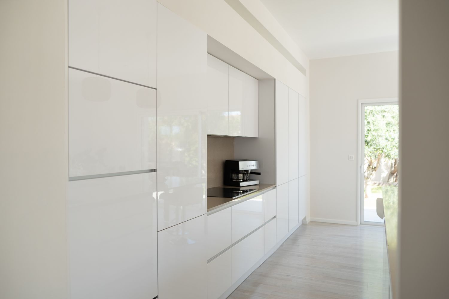 Modern white kitchen interior with sleek minimalist cabinets, built-in appliances and bright natural lighting.