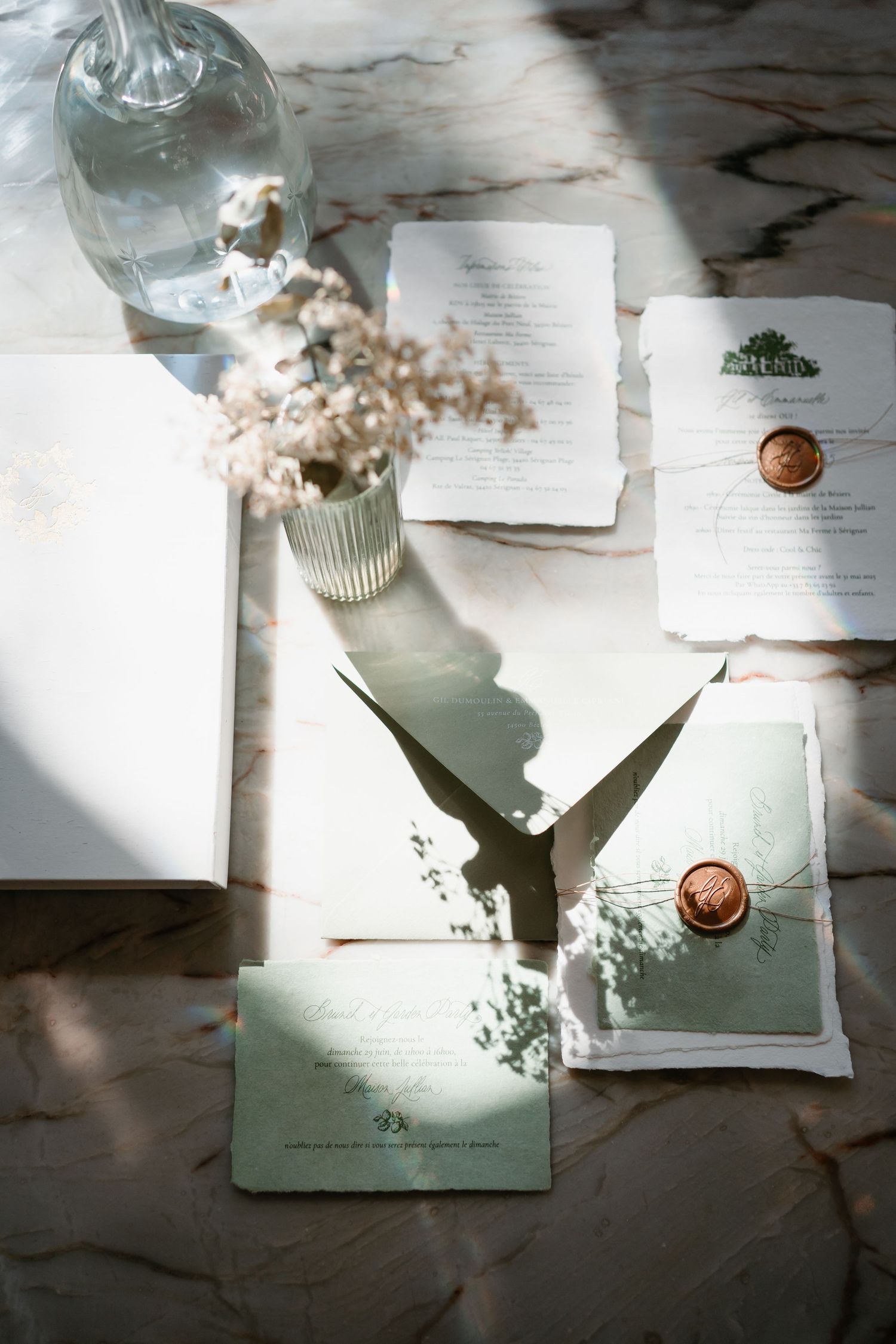 Artistic flatlay composition of white papers and glass bottles casting dramatic shadows on a textured surface.