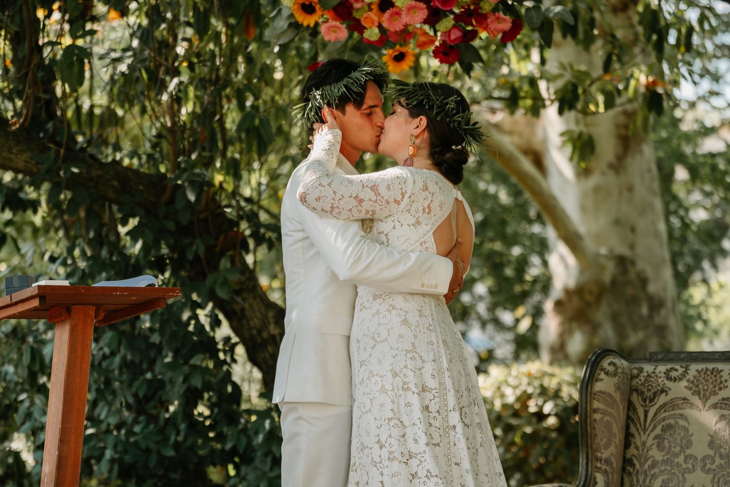 A couple shares an intimate embrace during their outdoor autumn wedding ceremony surrounded by fall foliage.