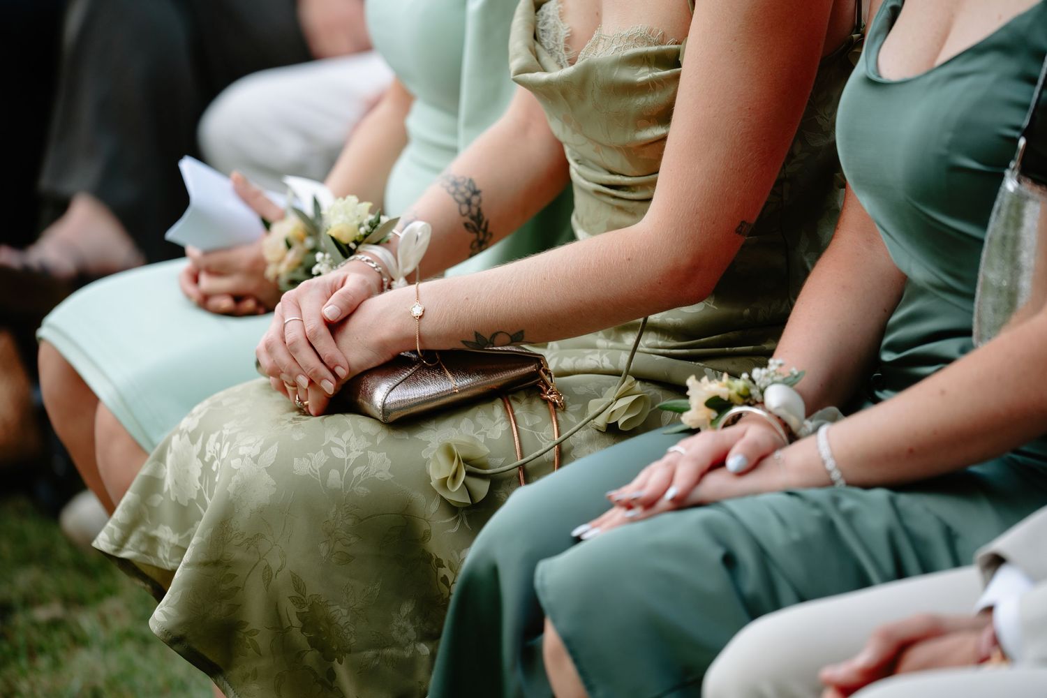 A row of people sitting outdoors wearing casual clothing while holding small objects in their hands.