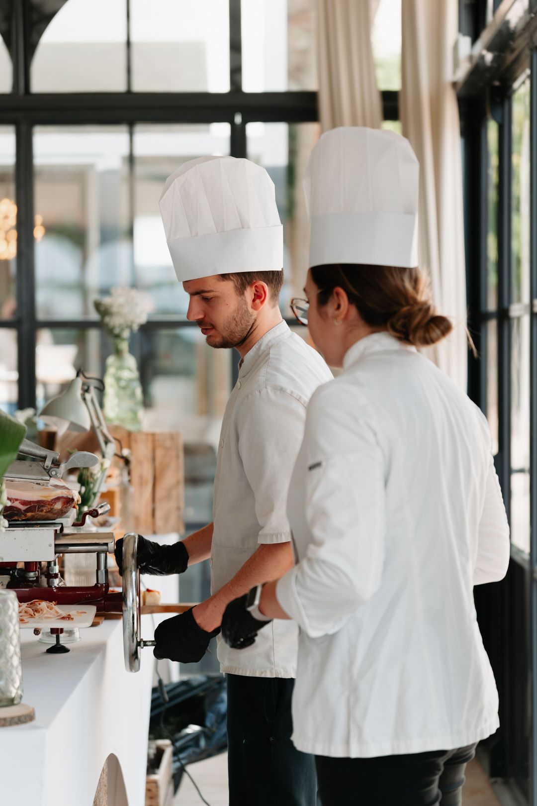 Professional chefs in white uniforms and hats working in a modern restaurant kitchen.