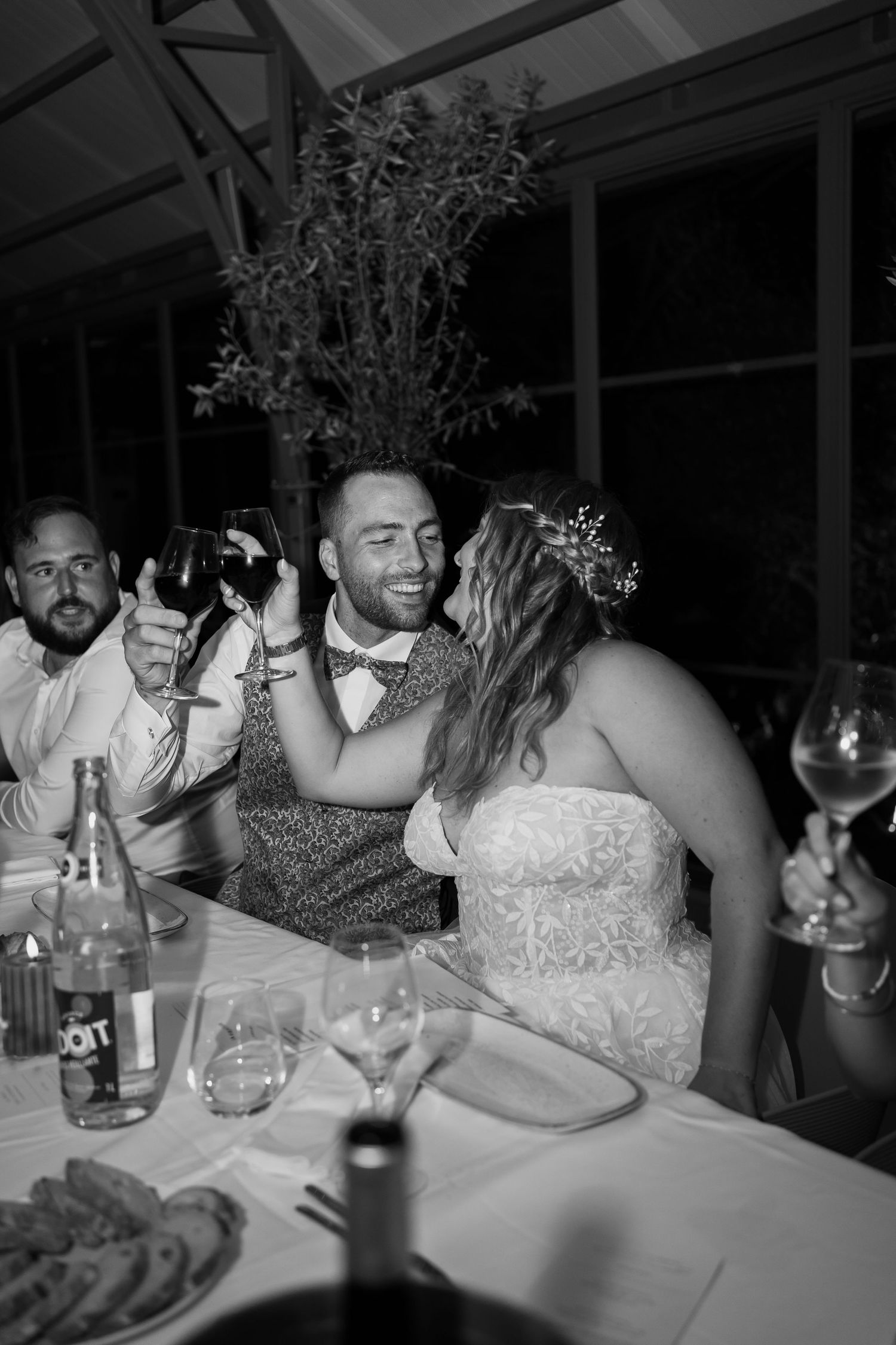 Wedding guests celebrate and laugh together at a reception table covered in white linens.