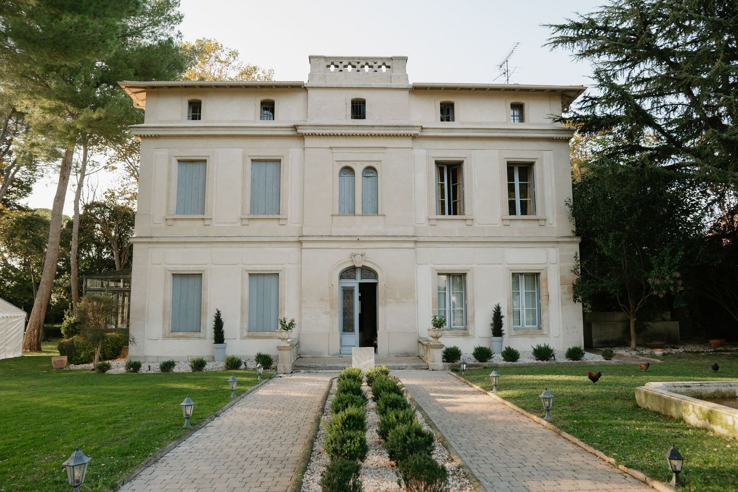 Exterior view of grand white Mediterranean villa with manicured grounds.