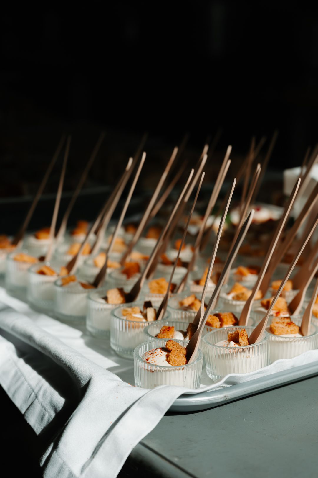 Rows of elegant appetizers on white paper liners with toothpicks arranged for a catered event.