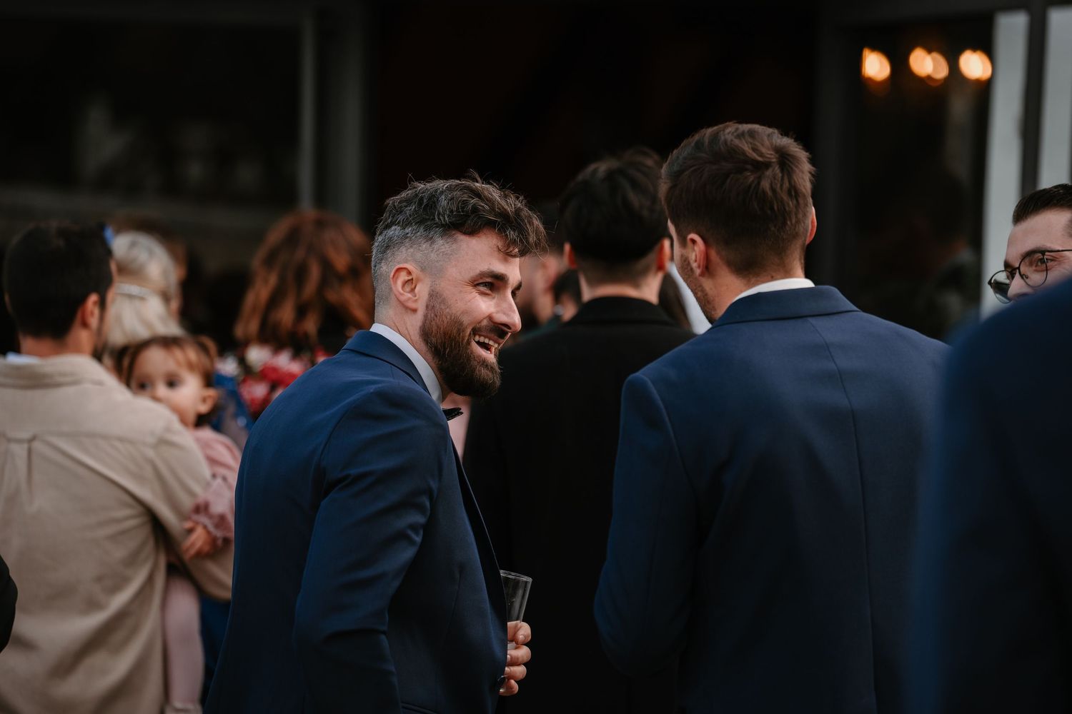 Wedding guests mingle during outdoor cocktail hour at dusk.
