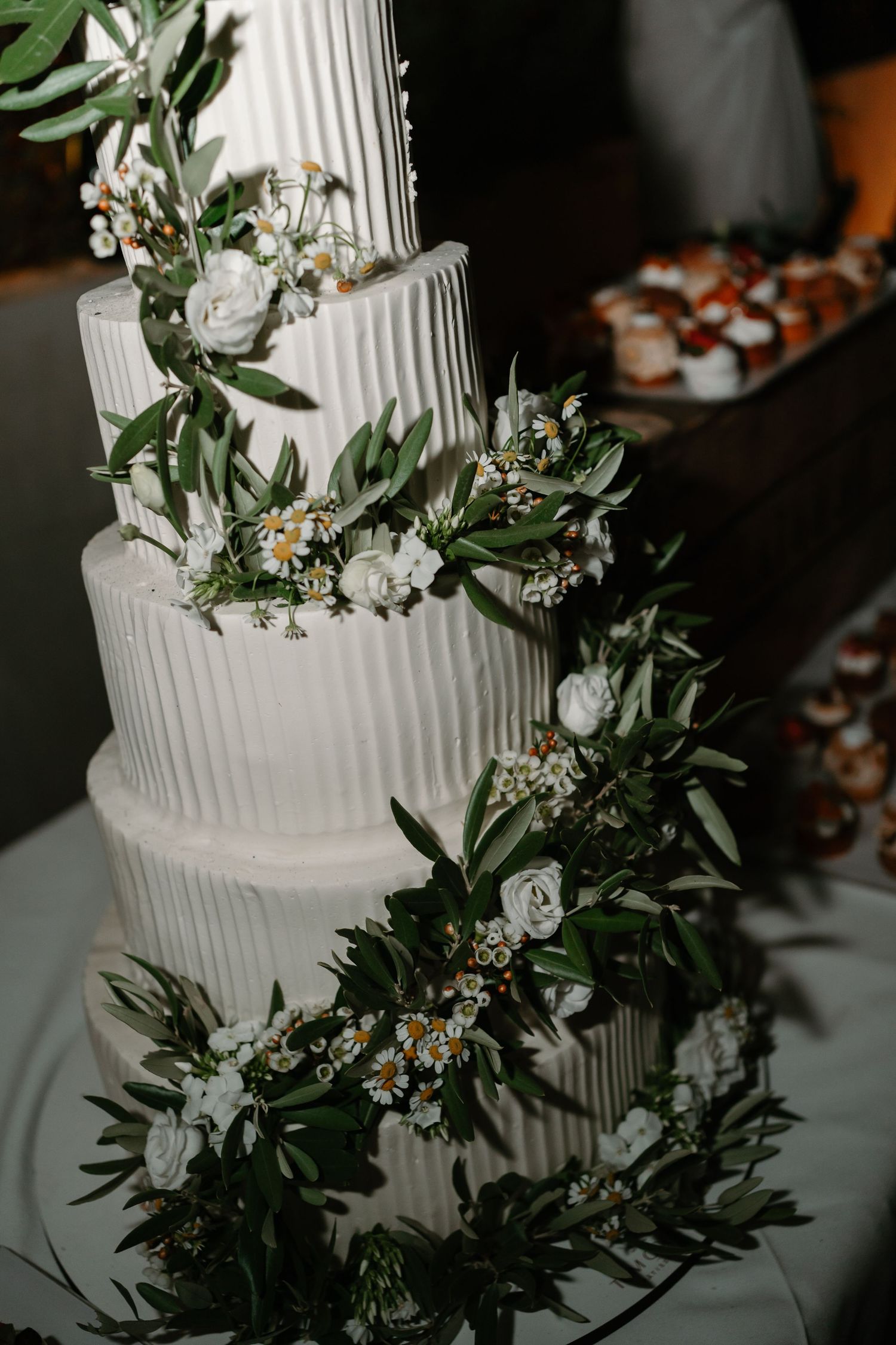 Close-up details of a white wedding cake decorated with delicate green foliage and floral accents.