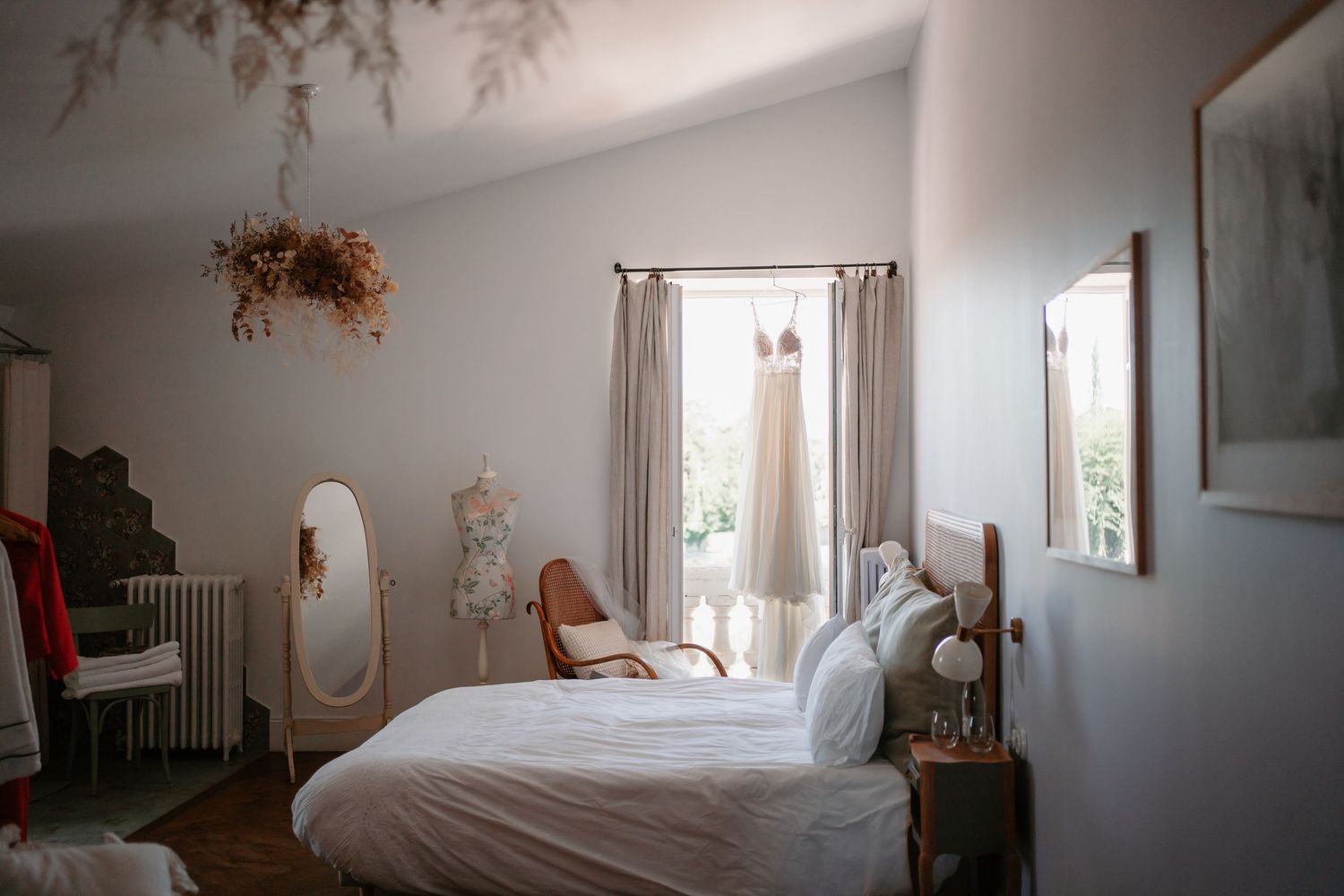 A panoramic view of a bright minimalist bedroom with white walls, natural light, and simple furnishings.