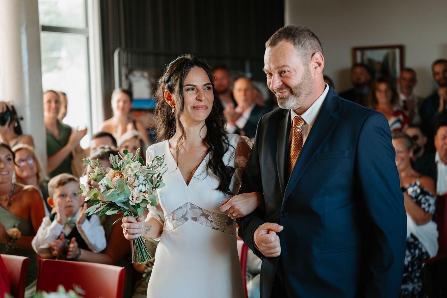 Wedding guests raise their glasses in celebration during a toast at an elegant indoor reception.