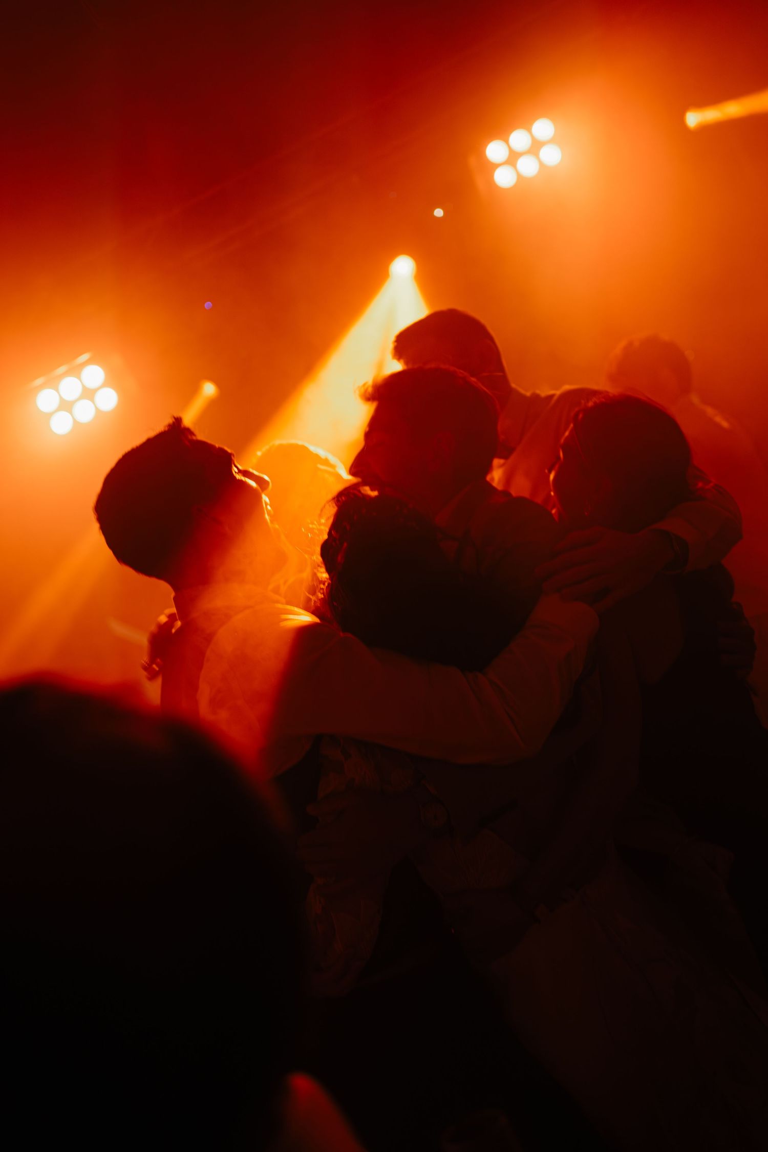 Silhouettes of people dancing in a nightclub with dramatic orange lighting and smoke effects creating an atmospheric scene.