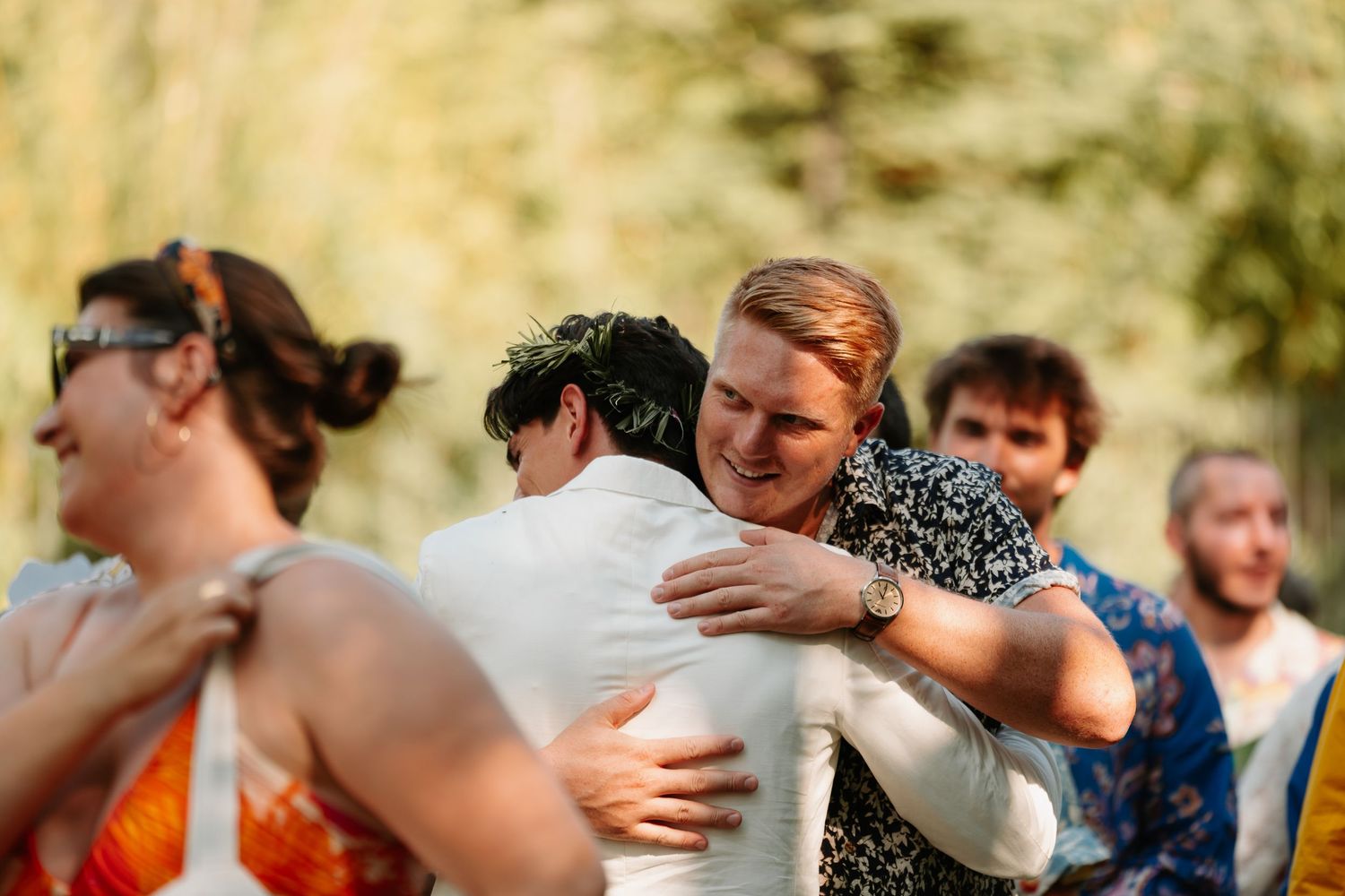 A sequence of wedding guests embracing and hugging during an emotional outdoor celebration.