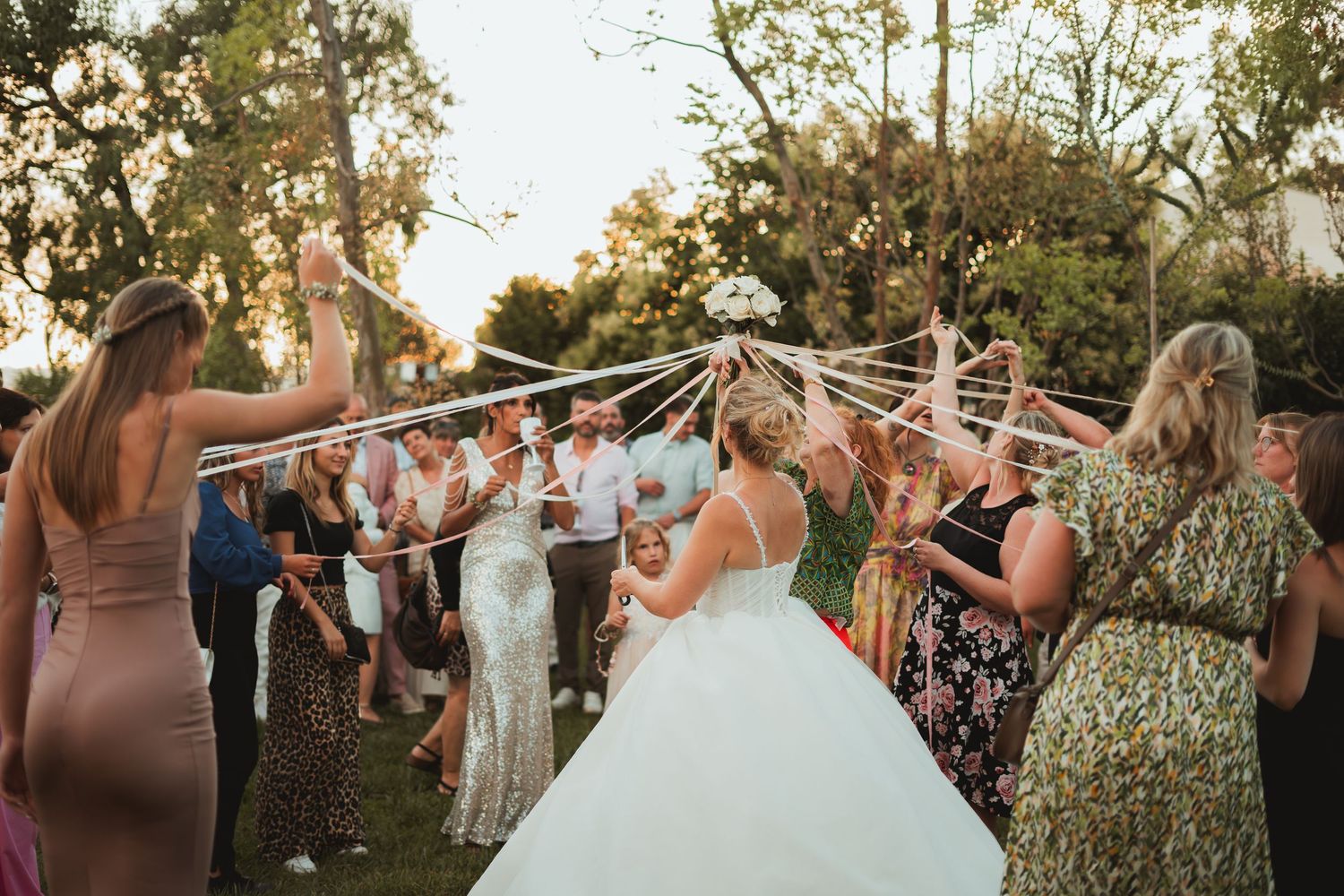 Wedding party celebrates outdoors during golden hour at a backyard reception.